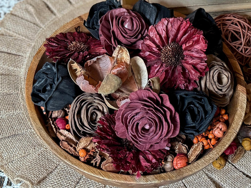 Wooden bowl filled with dried botanicals and wood flowers and herbs on a textured surface