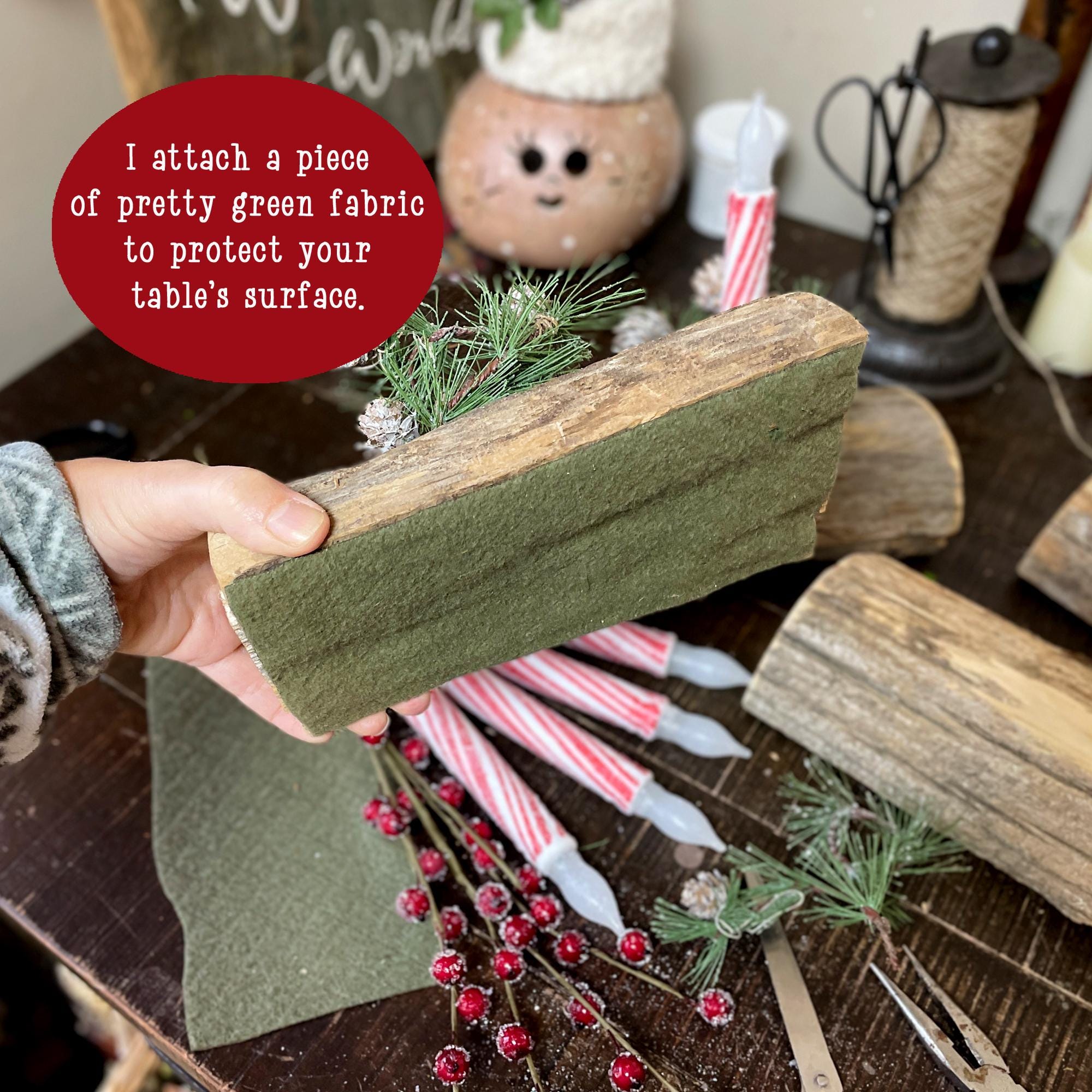 Person holding a piece of green fabric over a decorated table with Christmas decorations.
