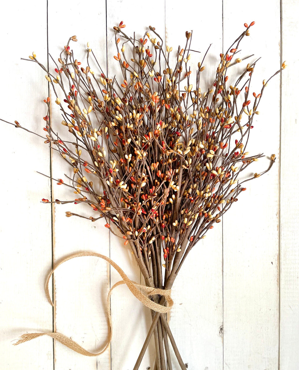 Bouquet of  autumn branches with small berries on a white wooden background.