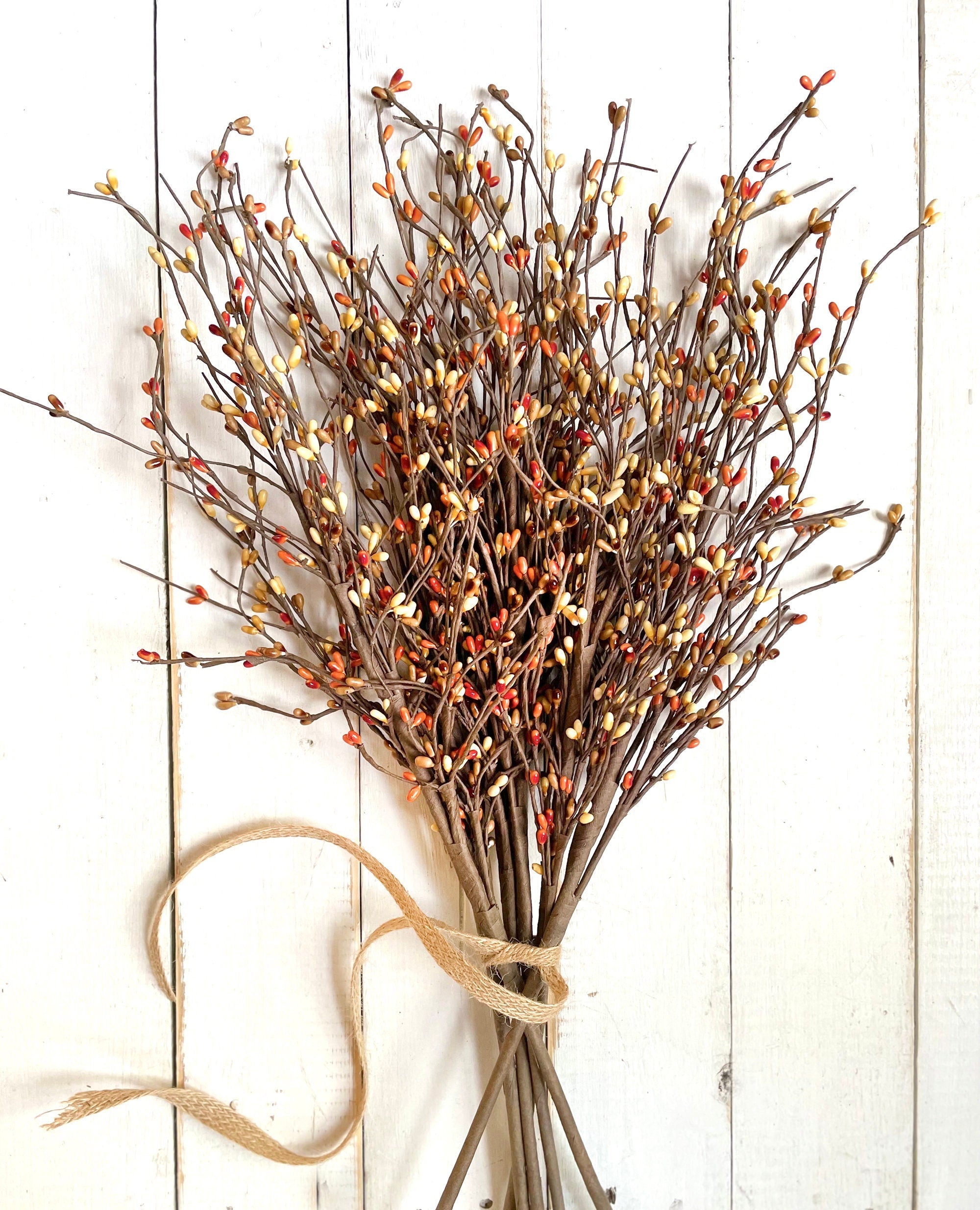 Bouquet of  autumn branches with small berries on a white wooden background.