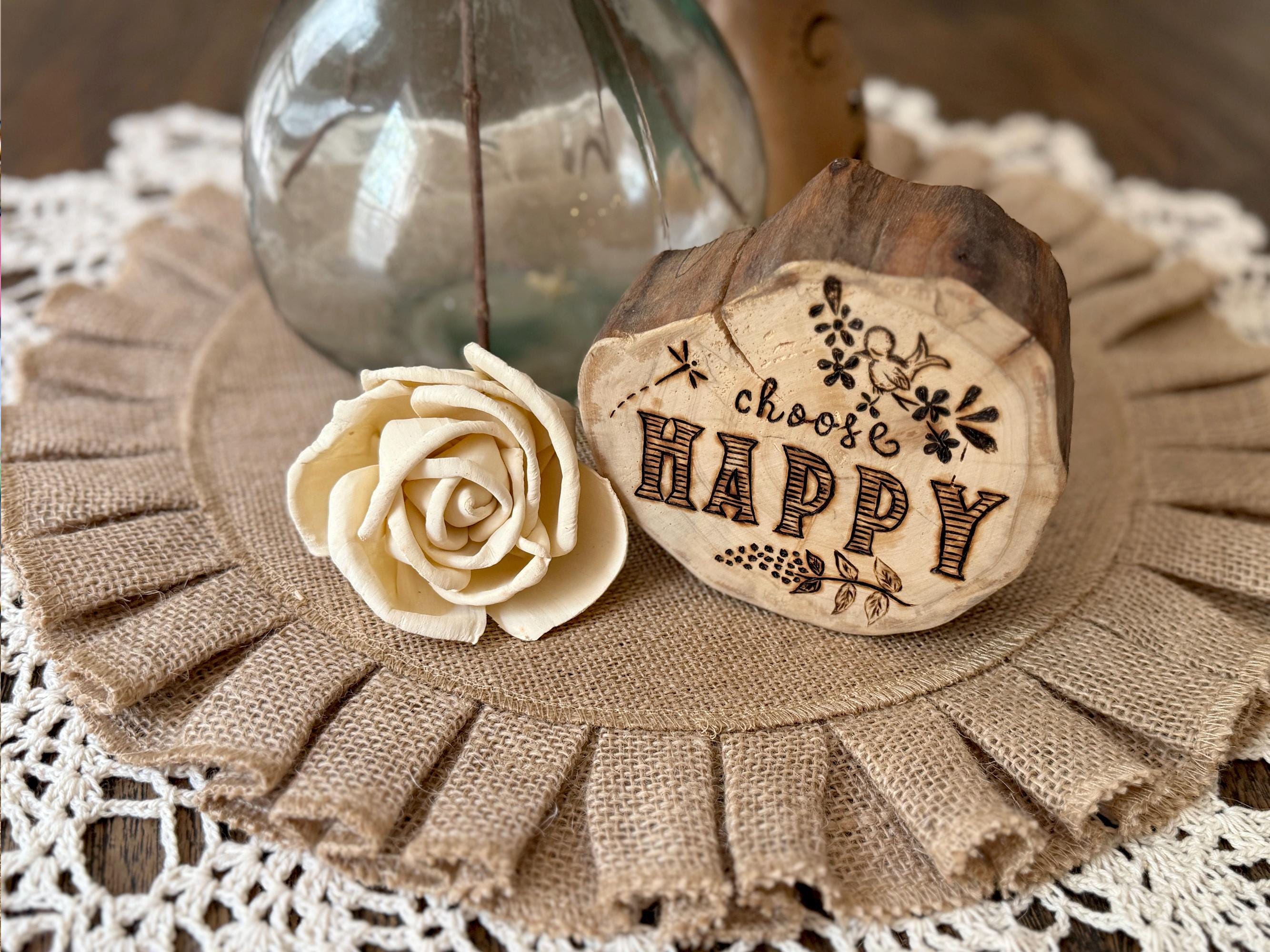 Wooden heart-shaped block with 'Choose Happy' engraving on a decorative surface with a rose.