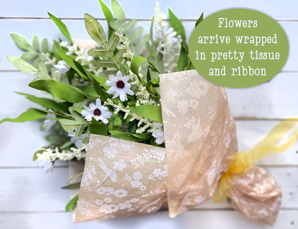 Bouquet of flowers wrapped in pretty tissue and ribbon on a wooden surface