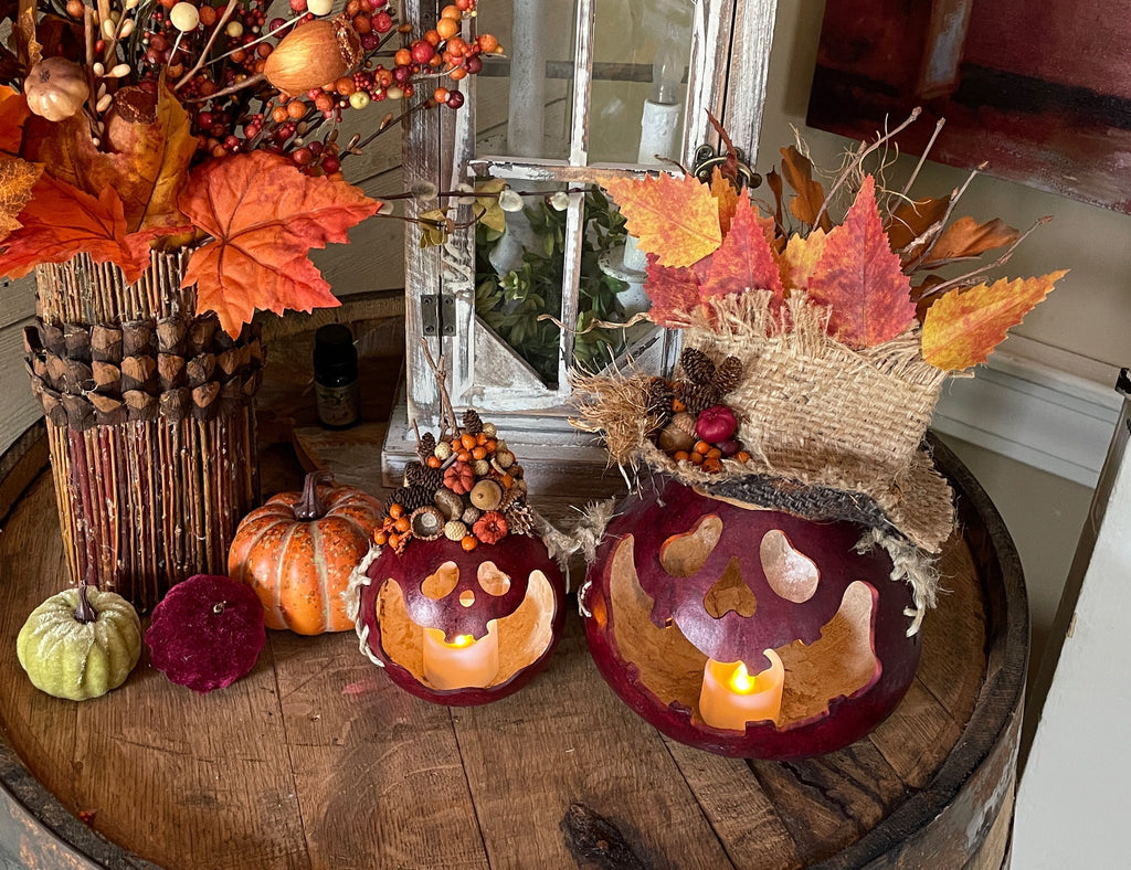 Decorative setup with pumpkins, candles, and autumn leaves on a wooden surface.
