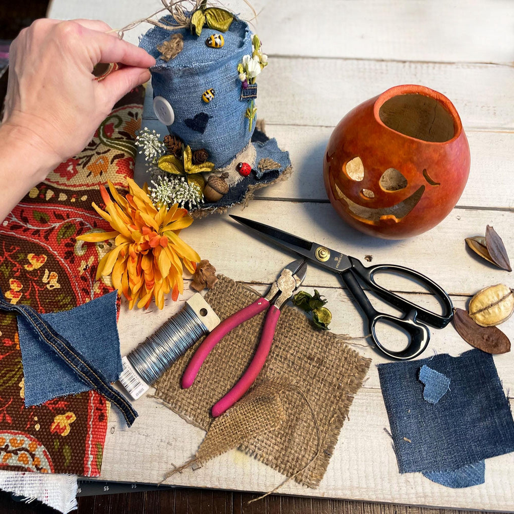 Crafting materials and tools on a wooden surface with a decorative pumpkin.