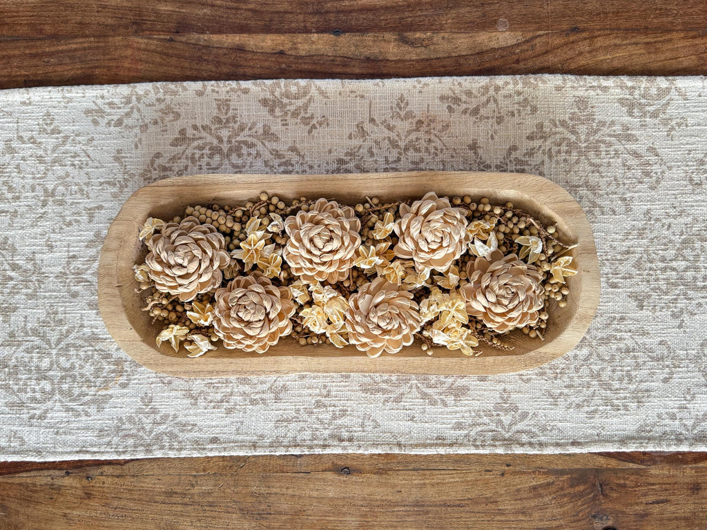 Wooden dowl bowl on coffee table with decorative flowers on a textured wooden surface