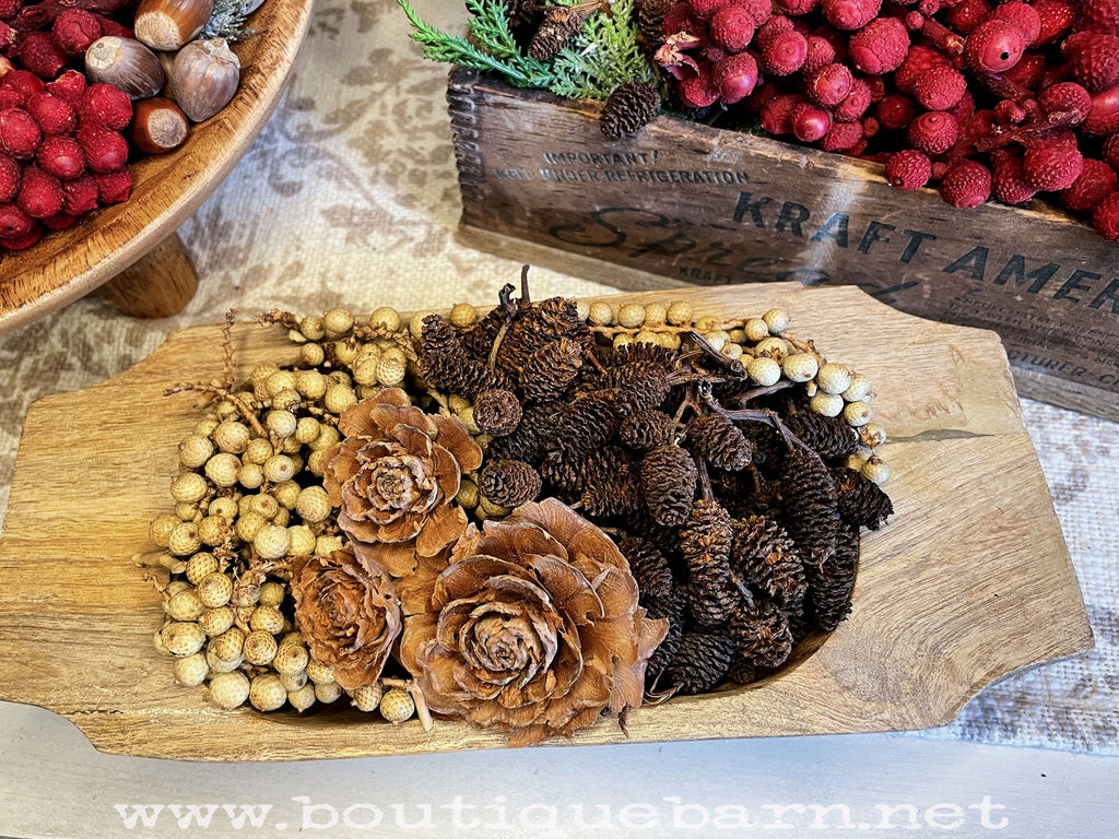 Decorative arrangement of pine cones and berries on a wooden board with a rustic background.