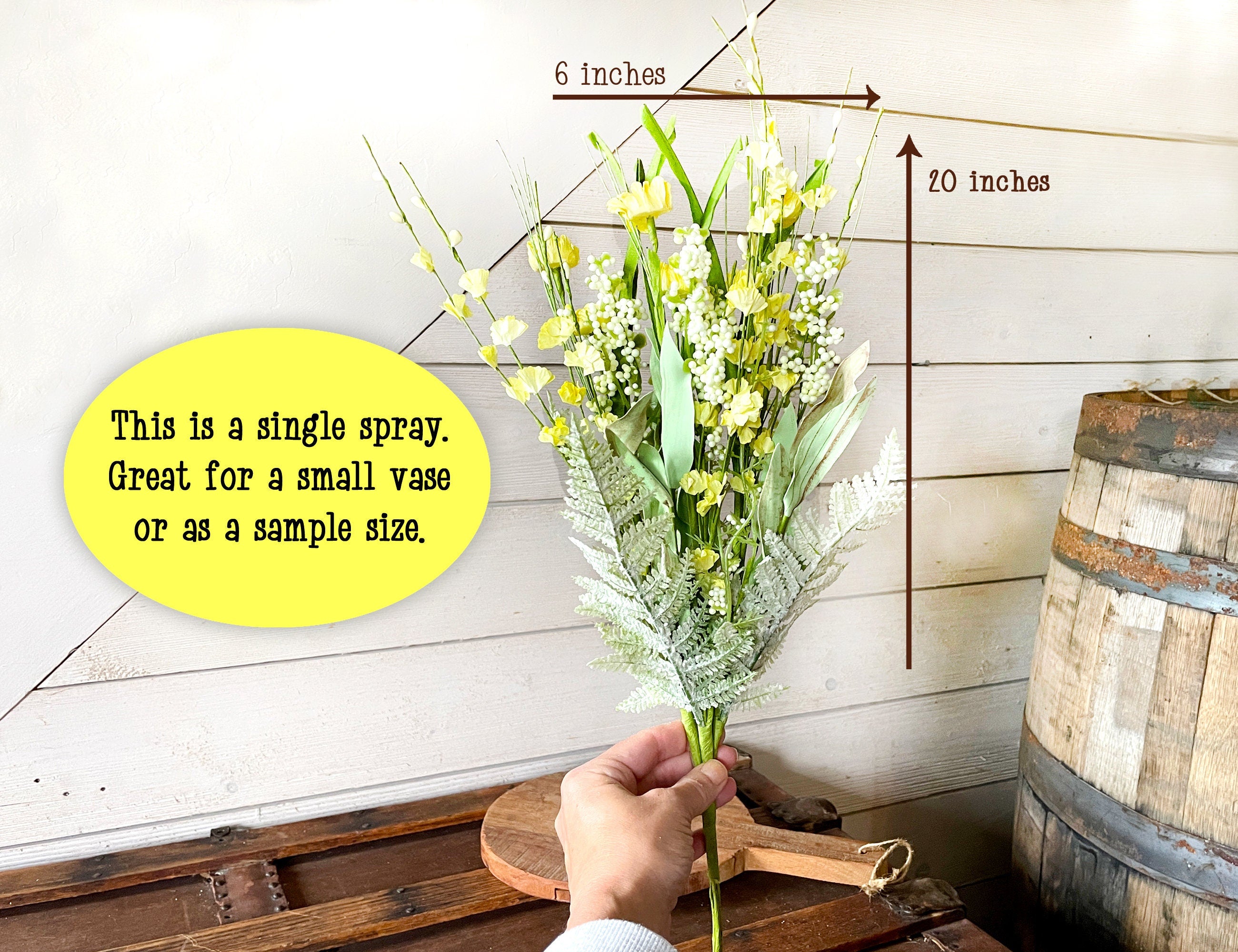 Hand holding a small bouquet of flowers with measurements and text on a wooden background