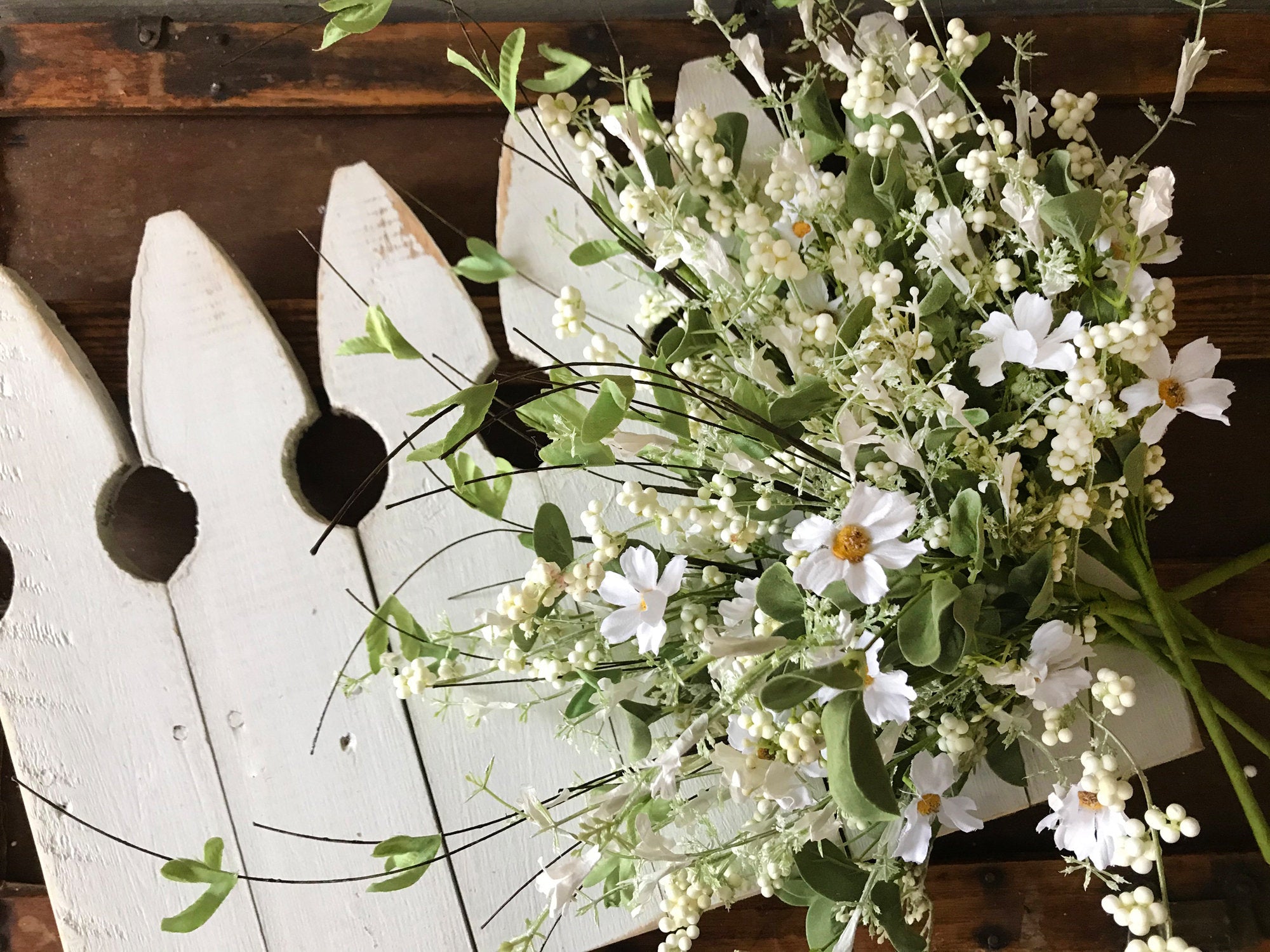 Bouquet of white flowers with green leaves against a wooden background