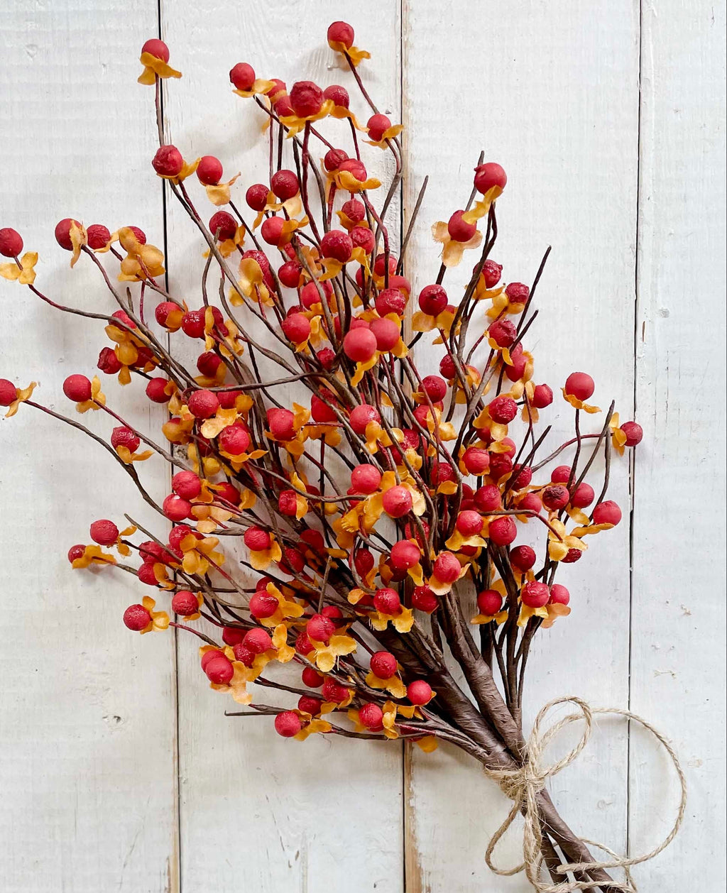 Bouquet of red and yellow berries tied with twine on a white wooden background