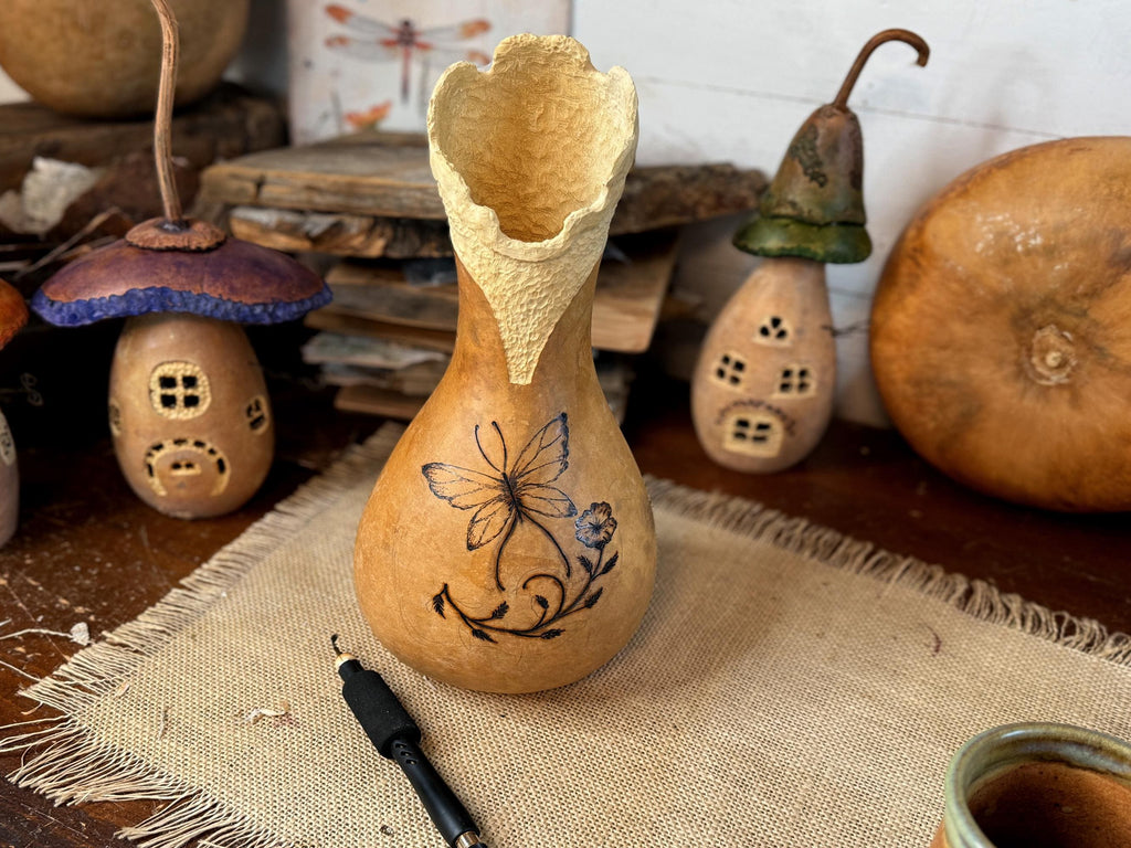 Decorative gourd with floral design on a rustic surface with other decorative items.