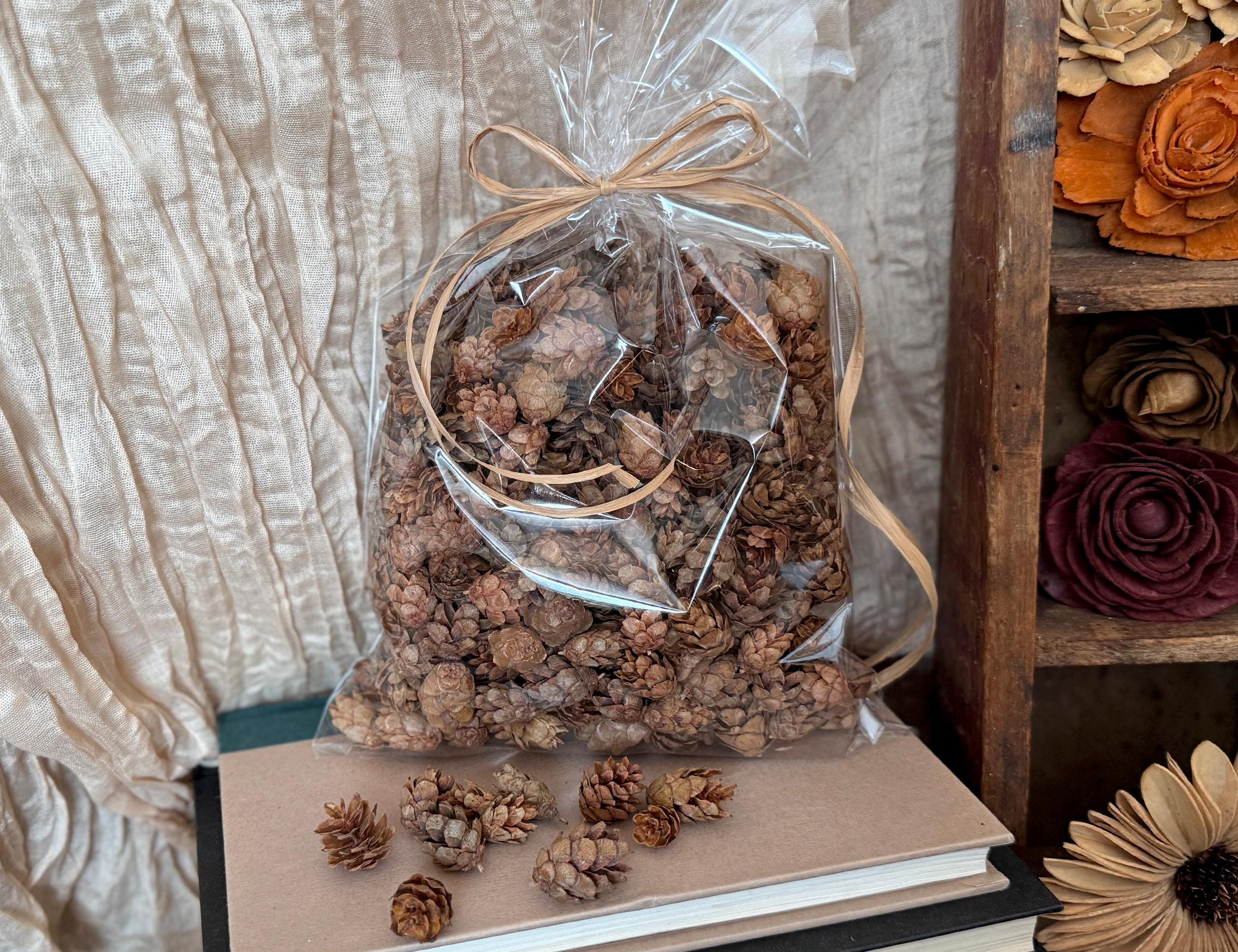 Bag of dried flowers tied with a ribbon on a surface with additional flowers in the background.