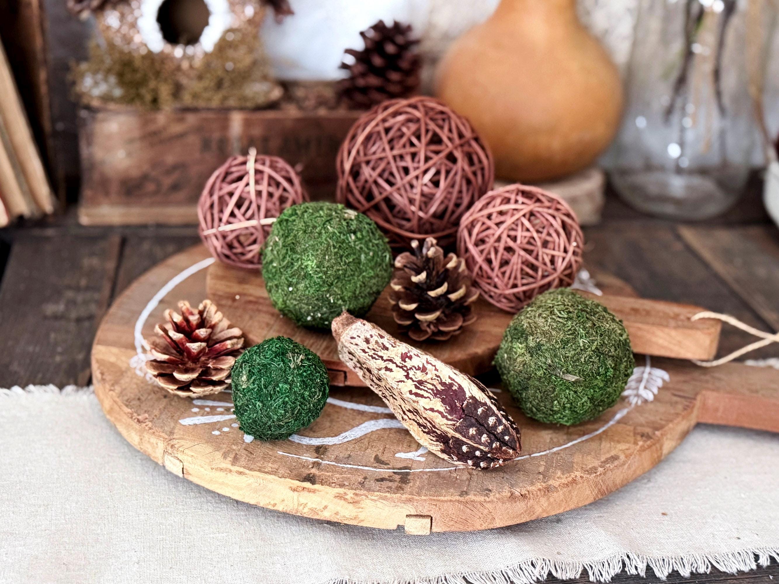 Decorative items including moss balls, pine cones, and rattan balls on a wooden board.