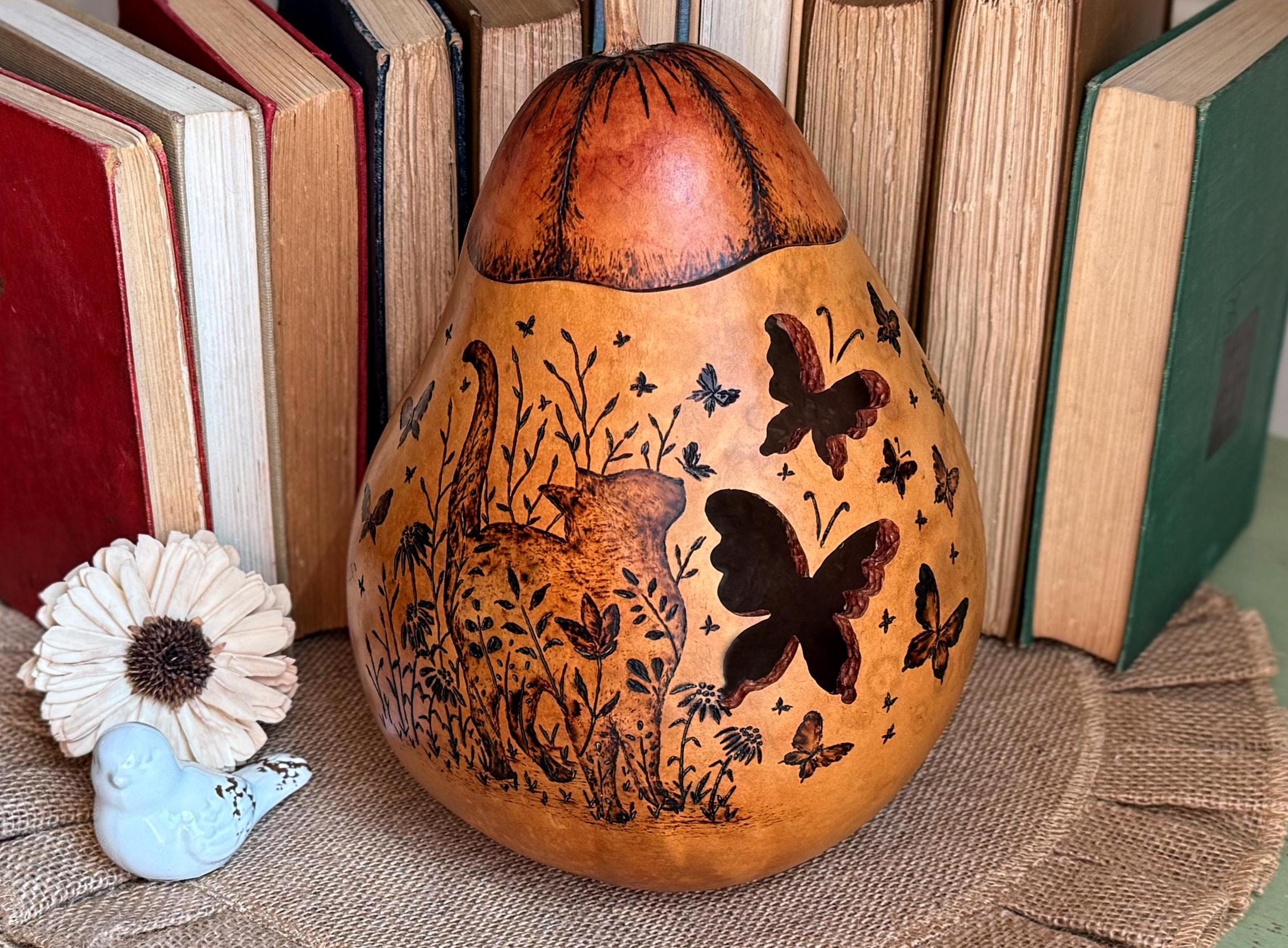 Decorative gourd with cat and butterfly designs in front of books