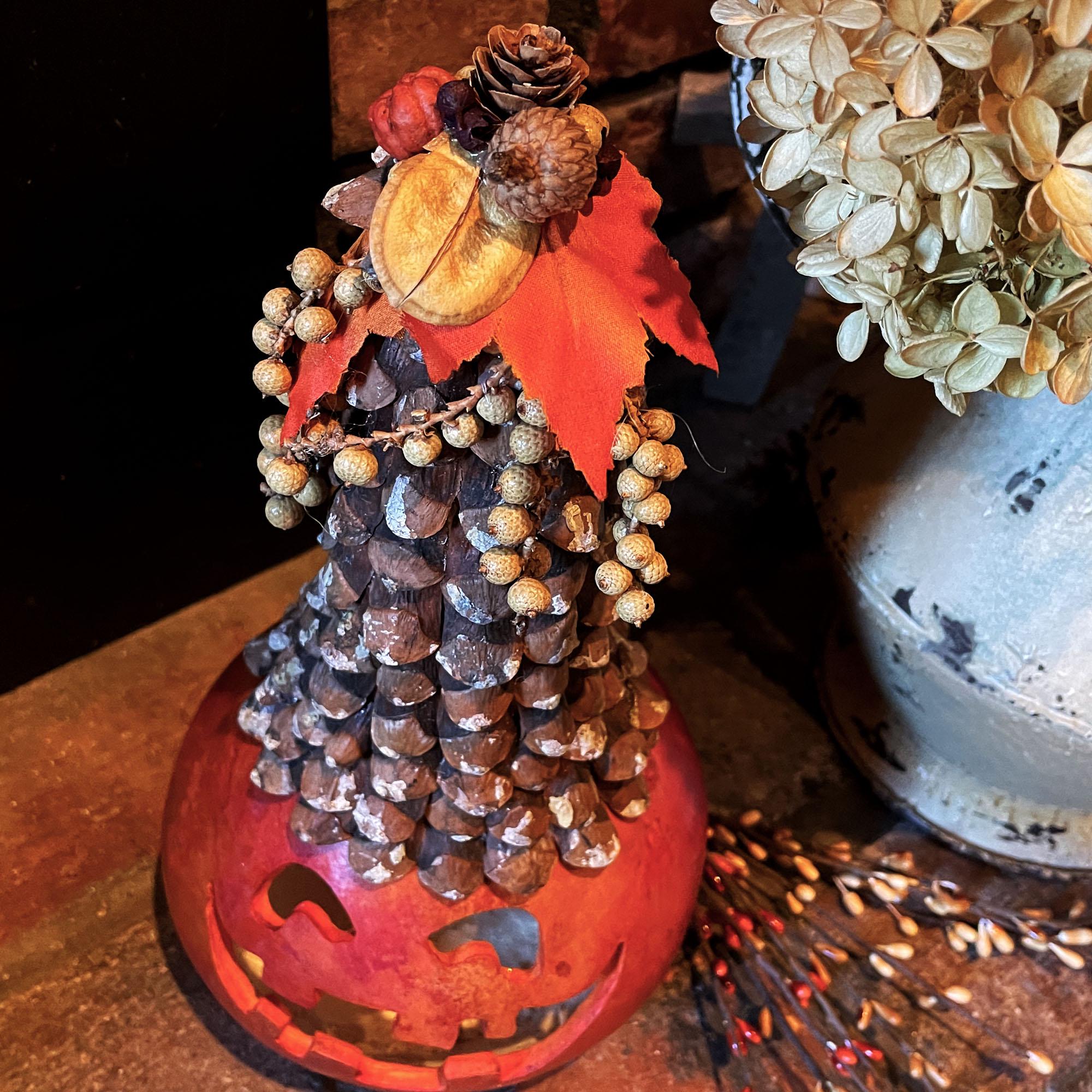 Decorative pinecone sculpture with a red base on a wooden surface