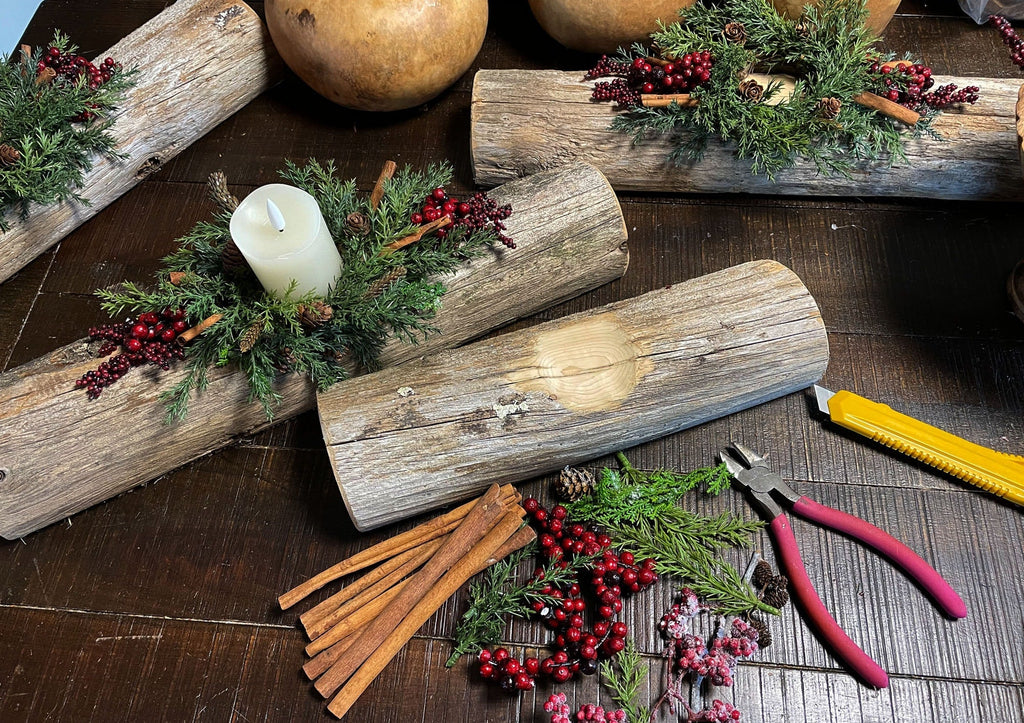 Decorative setup with wooden logs, candles, and festive elements on a table.