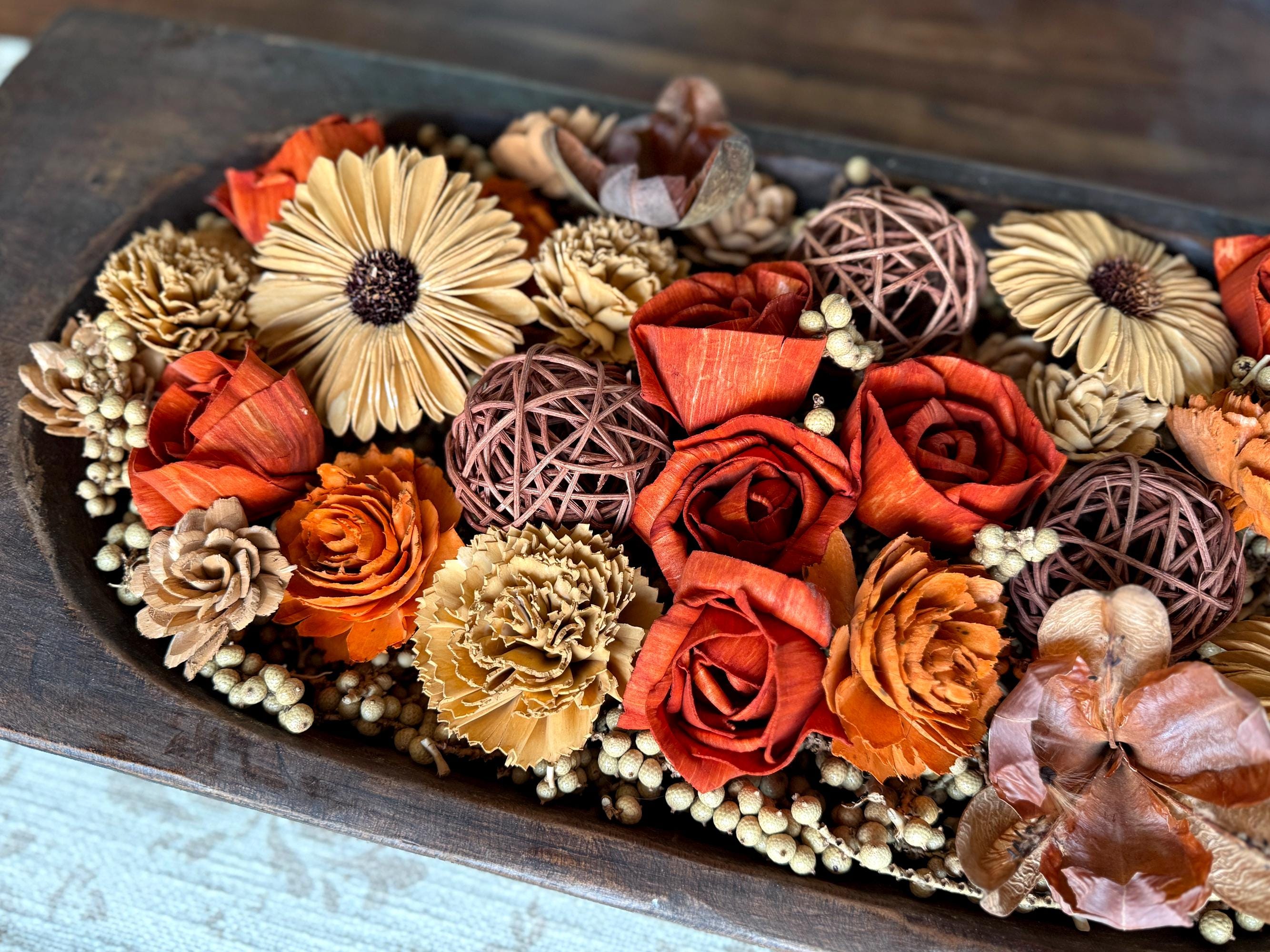 Decorative arrangement of dried  botanicals and wood flowers in a wooden dough bowl
