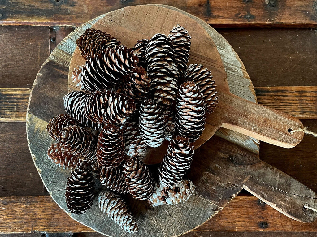 Wooden bowl filled with pinecones on a rustic wooden surface