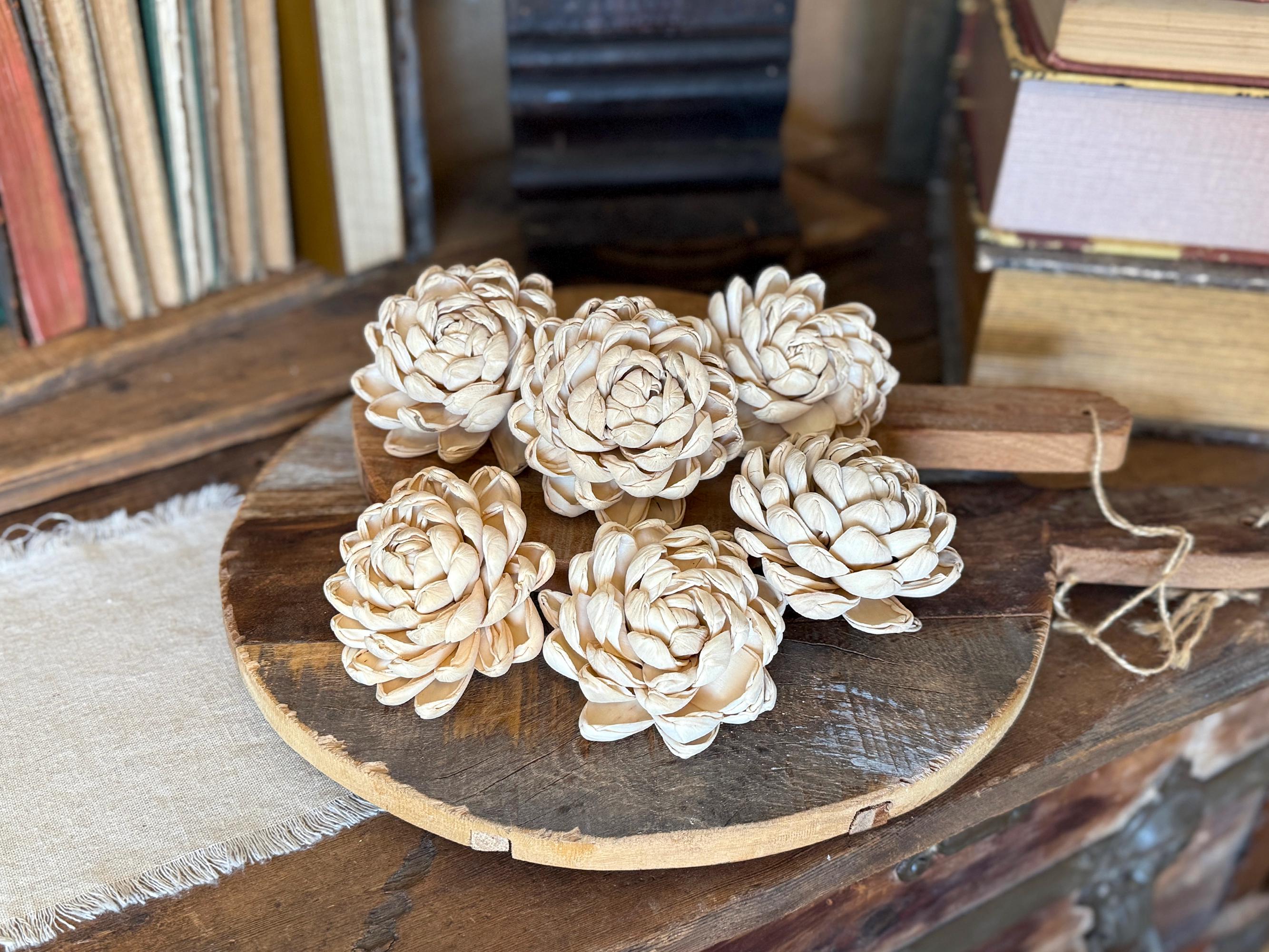 Wooden flower-shaped objects on a round wooden board with books in the background