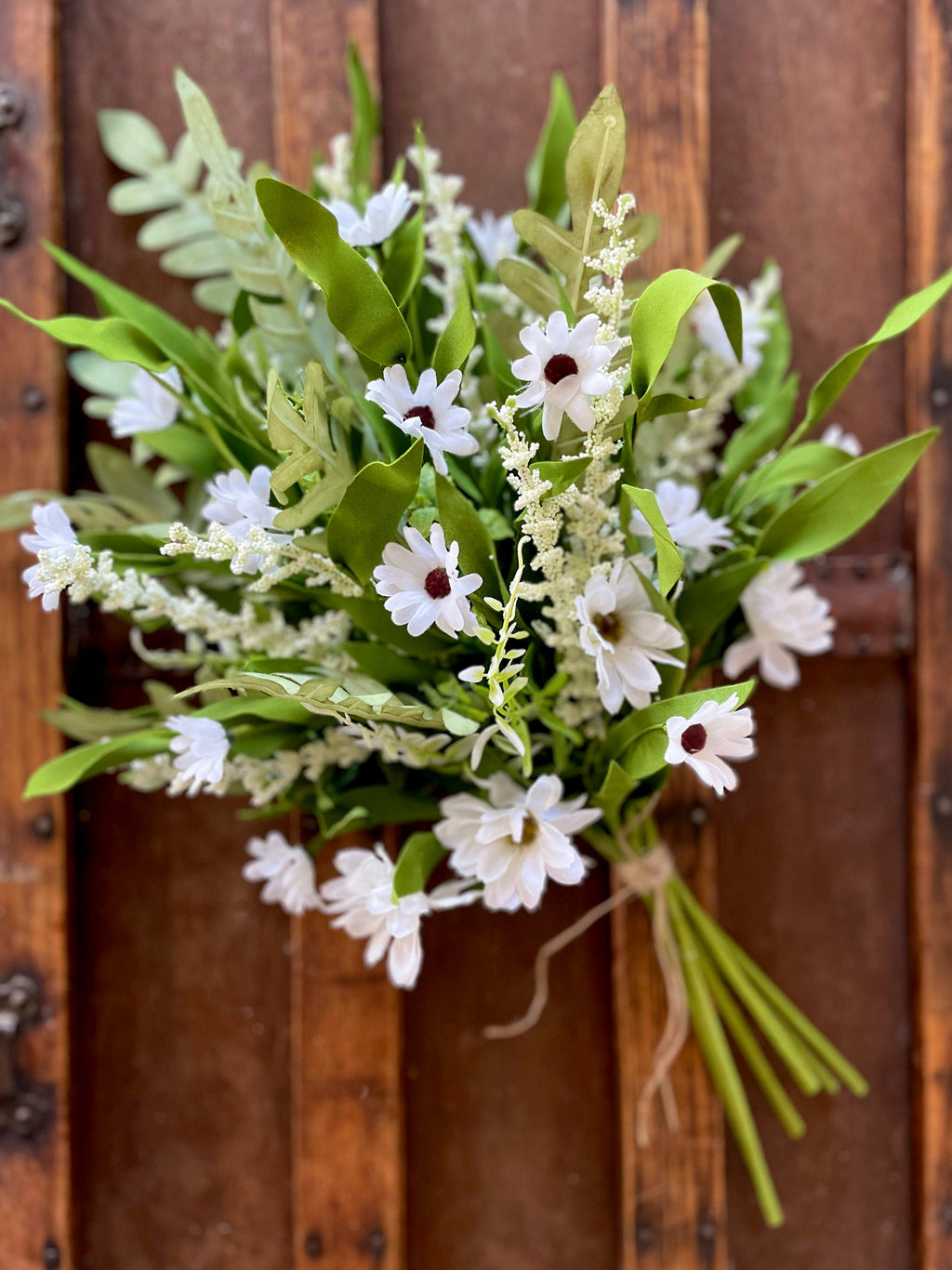 Bouquet of white flowers with green leaves against a wooden background
