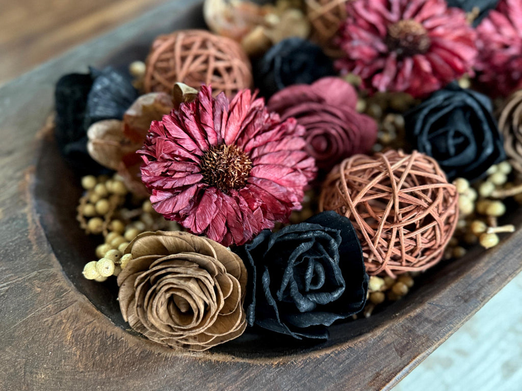 Decorative arrangement of dried berries and wood flowers and decorative balls on a coffee table.
