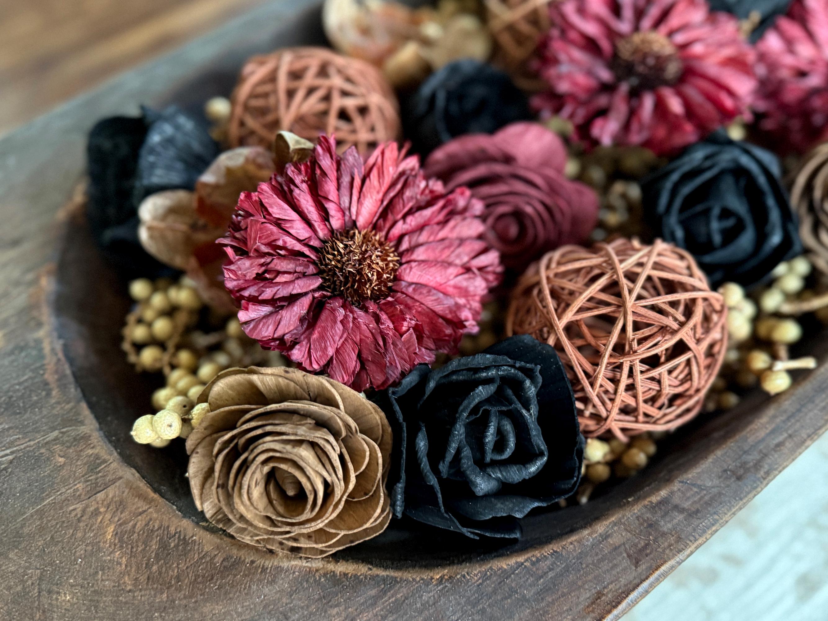 Decorative arrangement of dried berries and wood flowers and decorative balls on a coffee table.