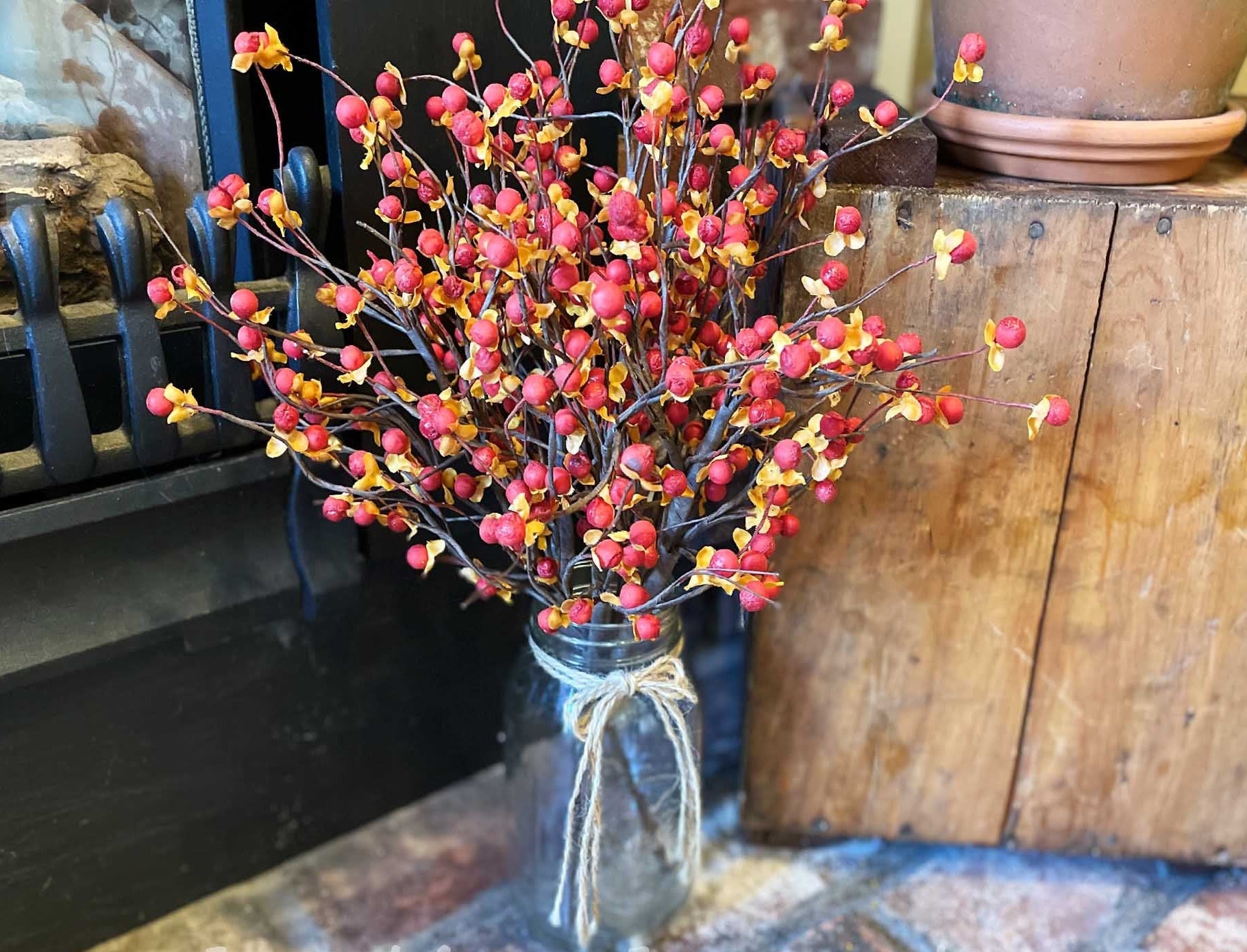 Bouquet of red and pink berries in a clear vase on a rustic wooden surface.