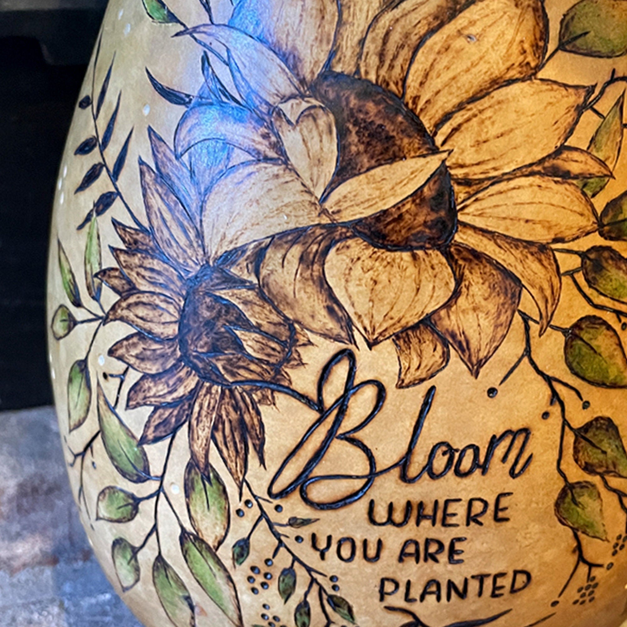 Decorative vase with floral designs and 'Bloom Where You Are Planted' text