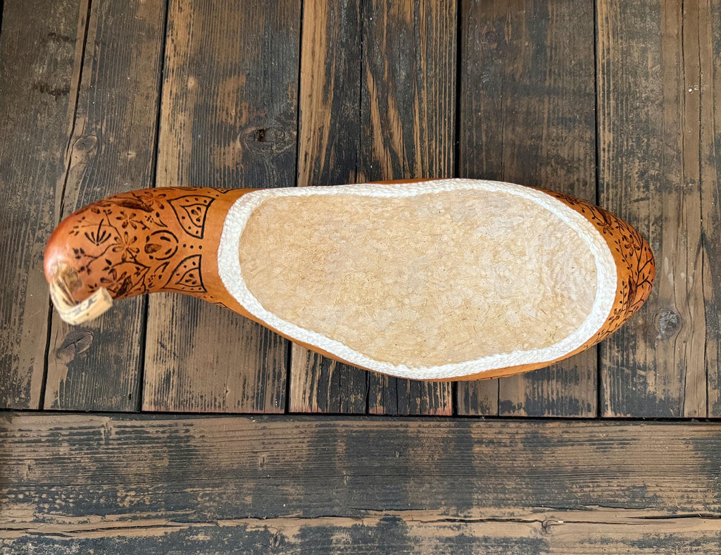 Wooden gourd with decorative carvings on a wooden surface