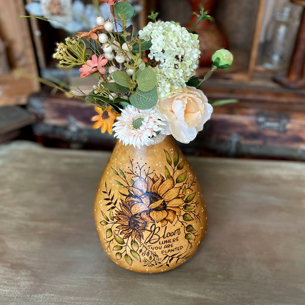 Decorative vase with floral design and text on a wooden surface