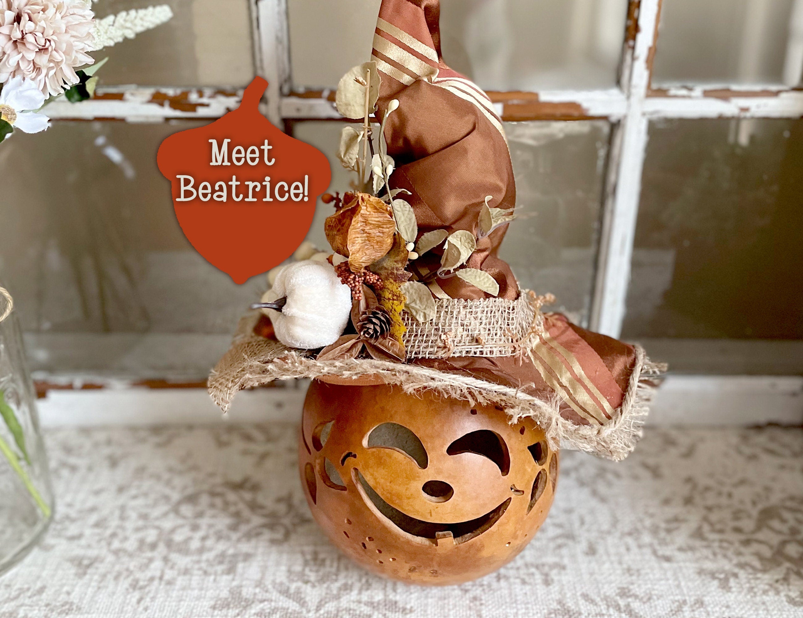 Decorative pumpkin with a face and a small figure on top, labeled 'Meet Beatrice!'.