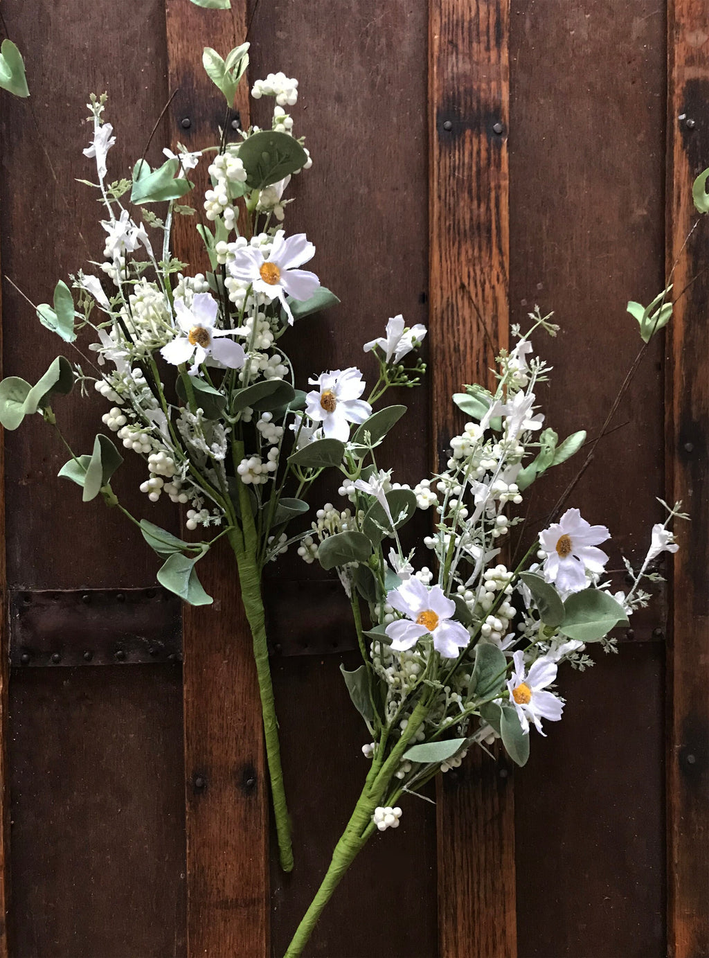 Bouquet of white flowers with green leaves against a wooden background