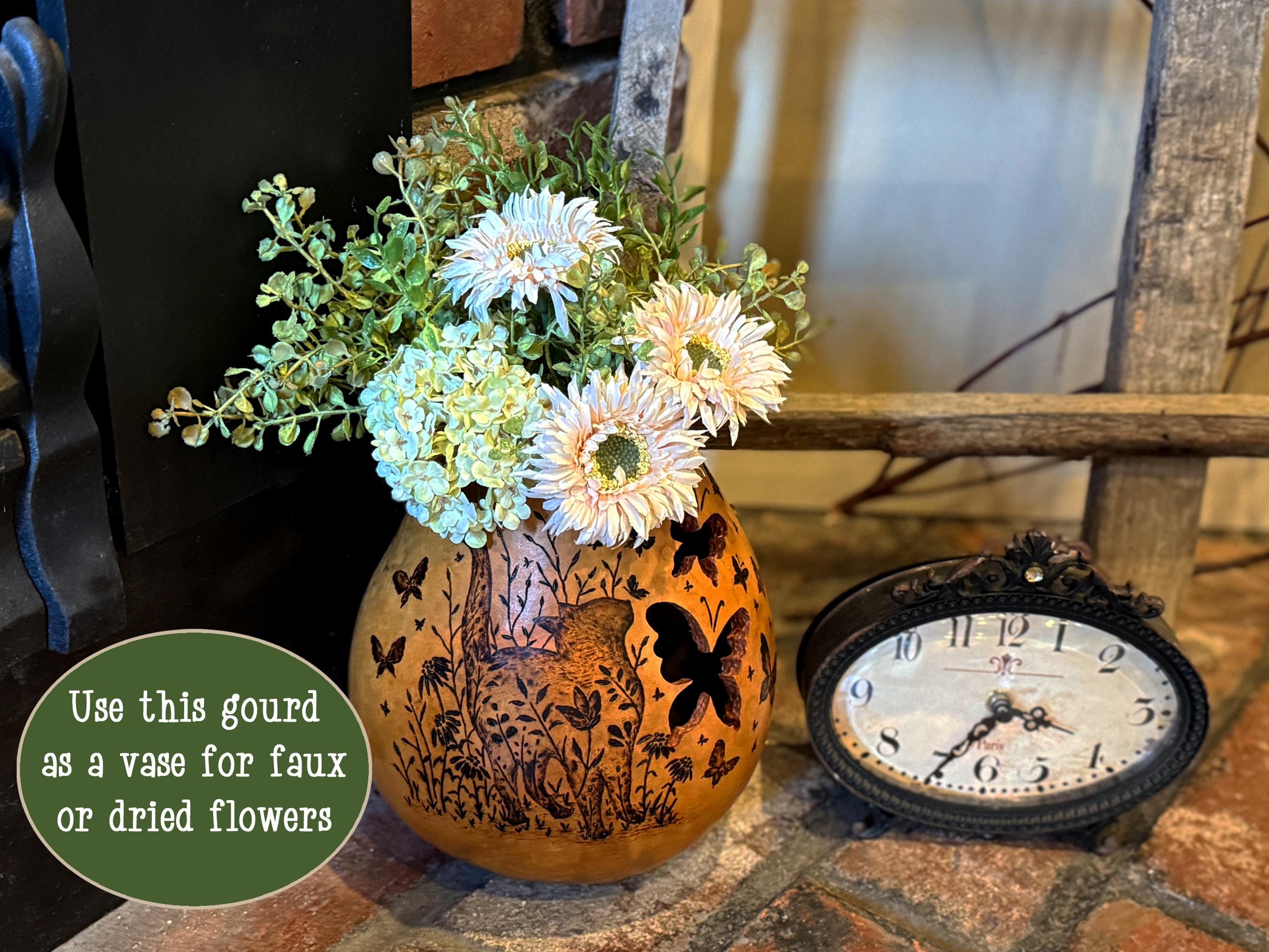 Decorative gourd with floral arrangement and vintage clock on a stone surface