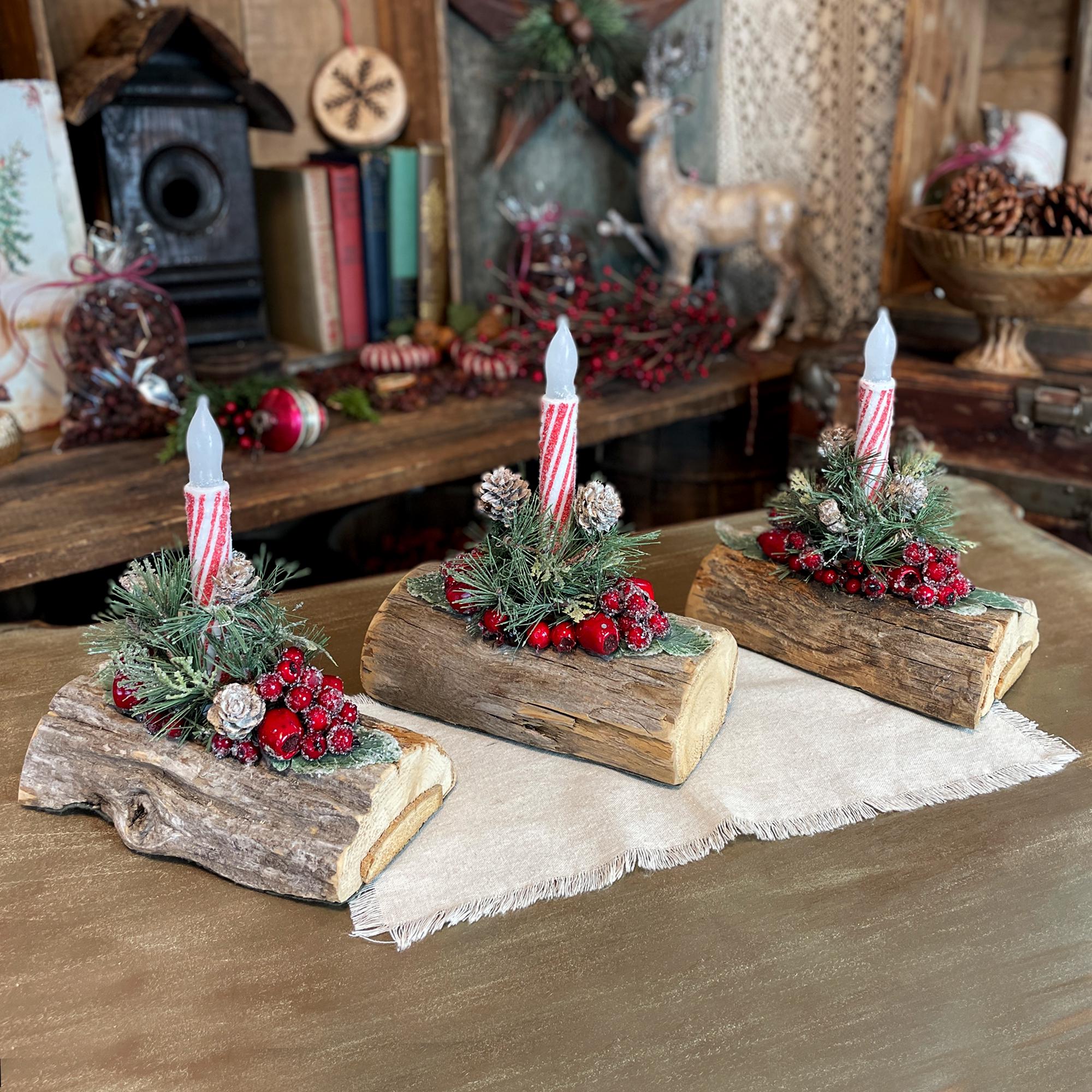 Decorative Christmas logs with candles and festive decorations on a wooden surface.