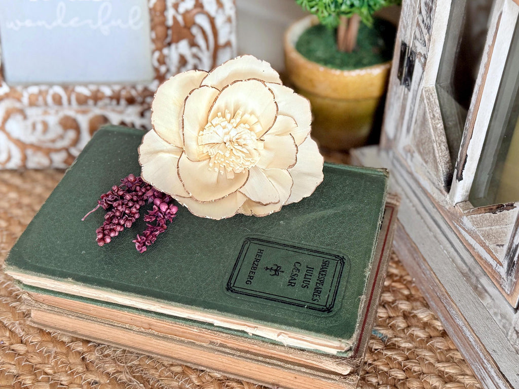 Stack of books with a decorative flower on top, placed on a textured surface.