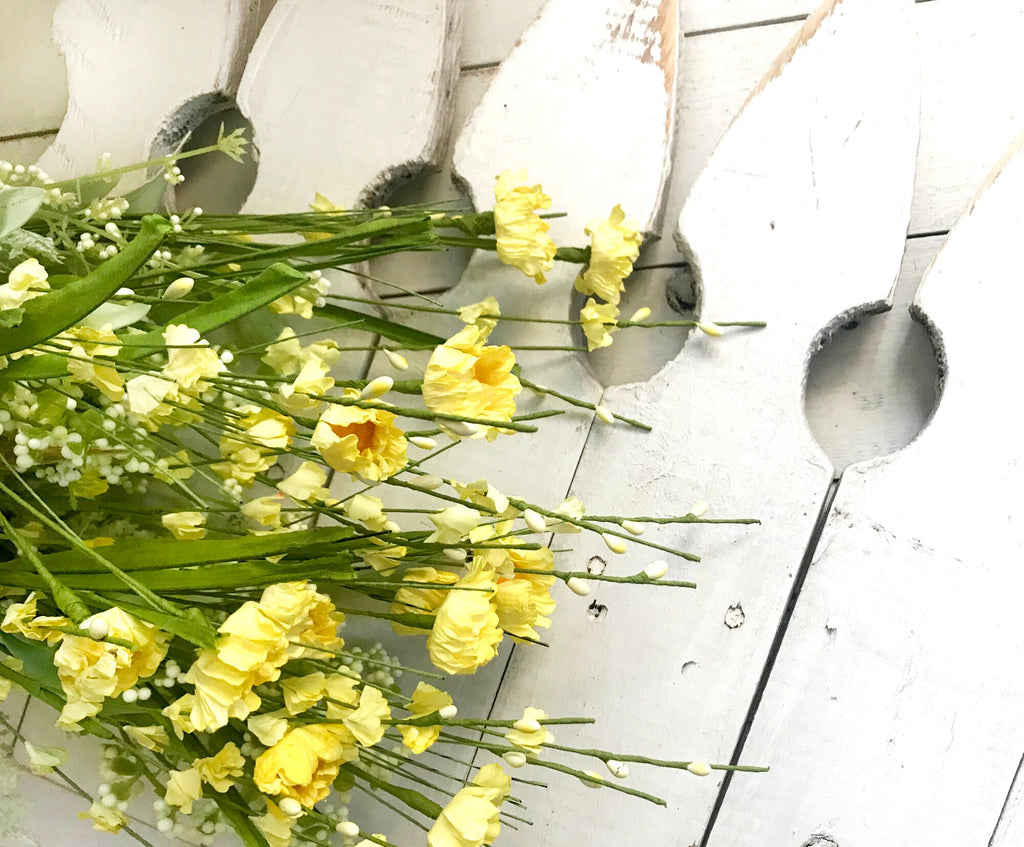 Yellow flowers on a white wooden surface with metal spoons.