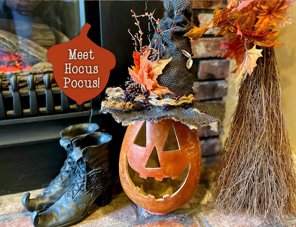 Halloween-themed decoration with a jack-o'-lantern, broom, boots, and 'Meet Hocus Pocus!' sign.
