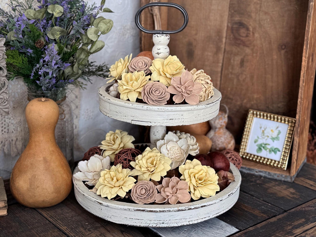 Two-tiered decorative stand with floral arrangements on a wooden surface.