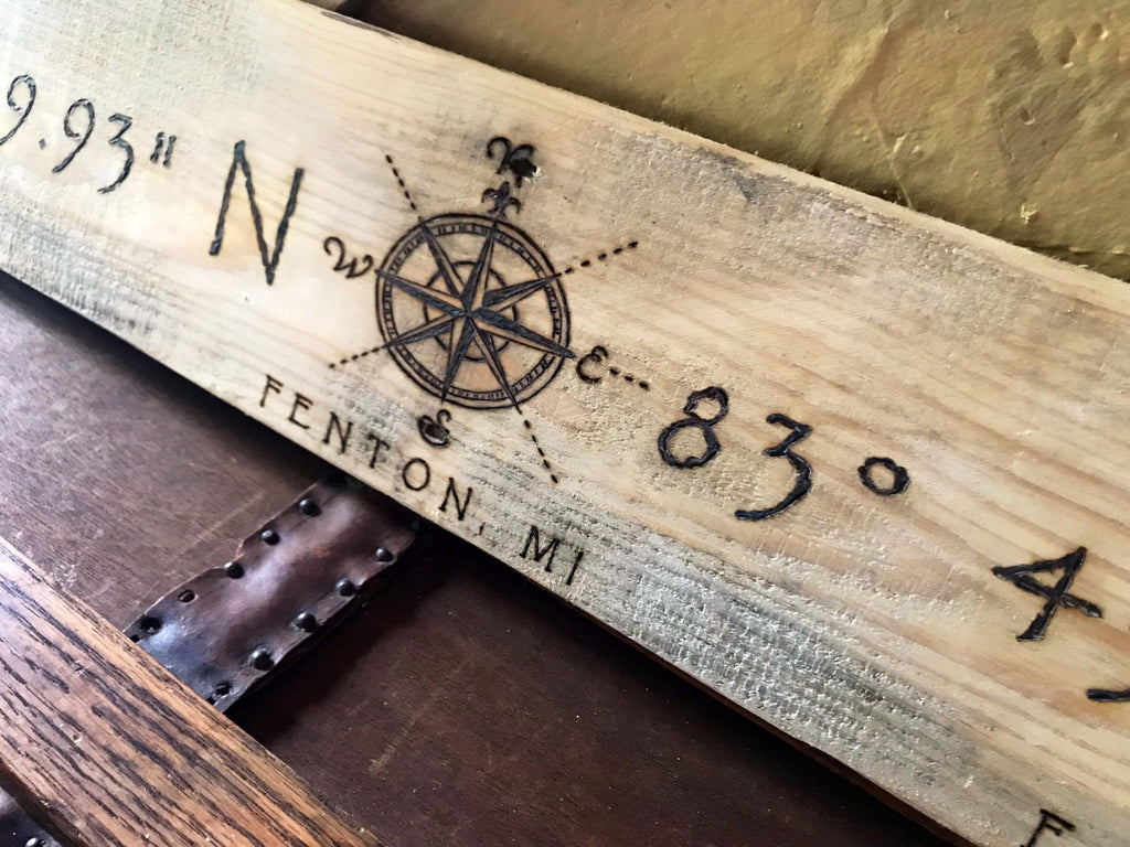 Wooden board with engraved compass rose and coordinates on a wooden surface