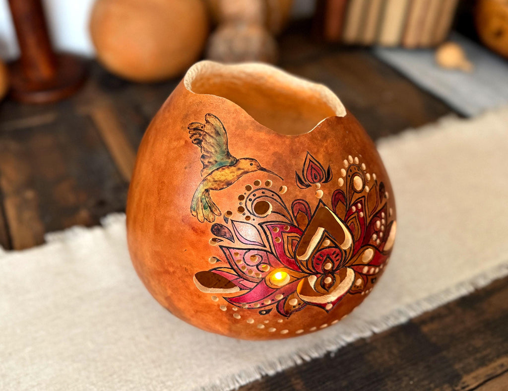 Decorative gourd lantern with intricate hummingbird designs on a wooden surface