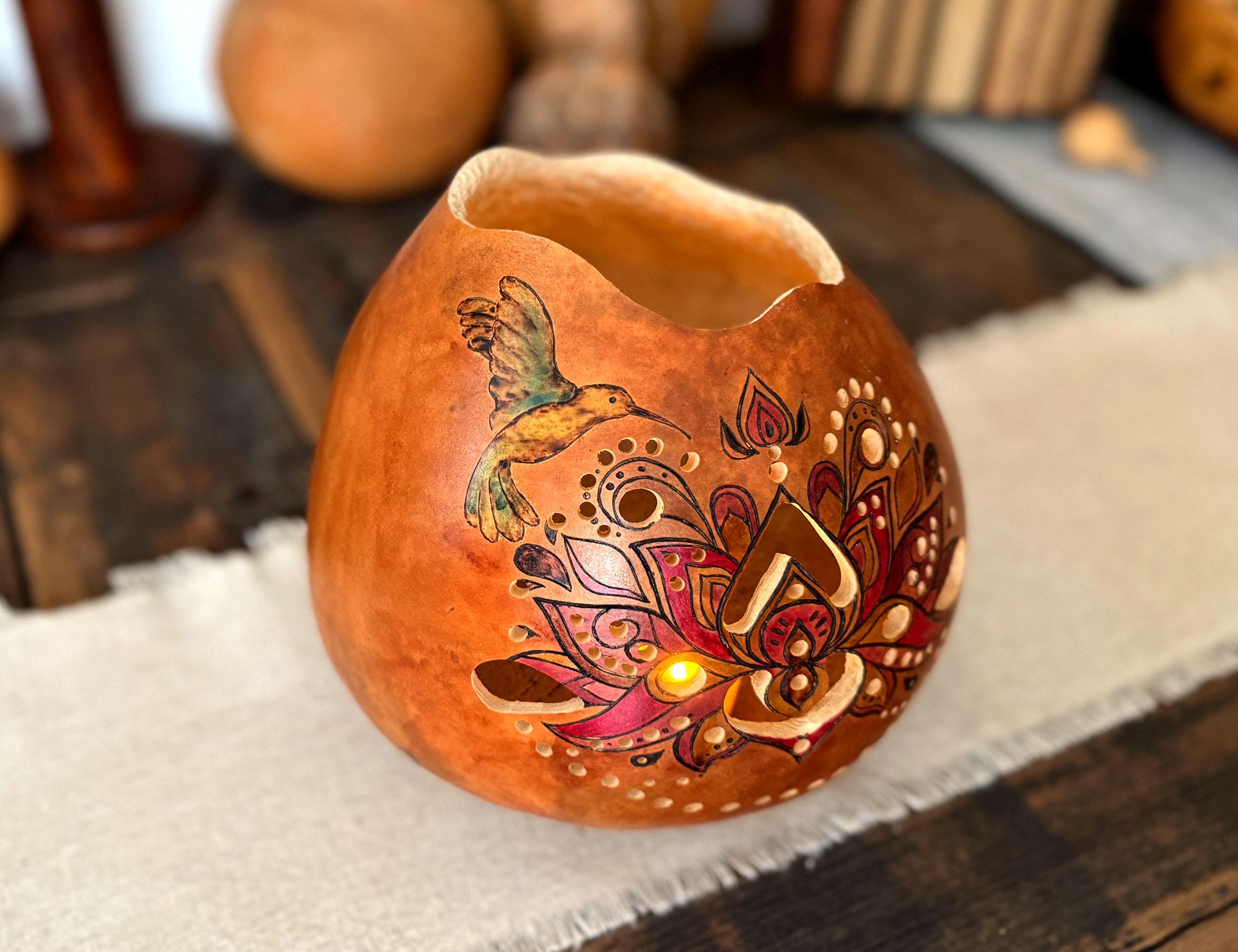 Decorative gourd lantern with intricate hummingbird designs on a wooden surface