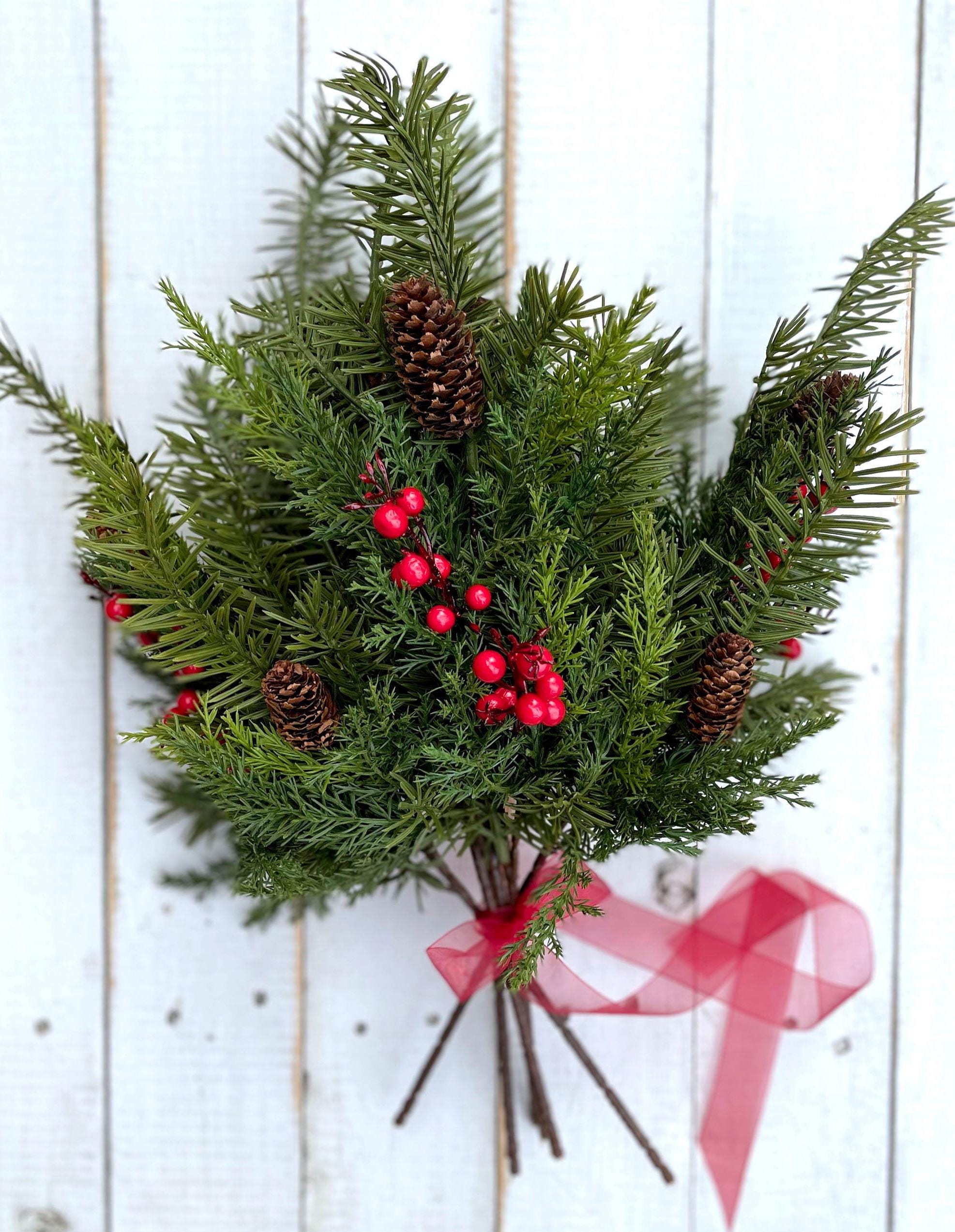 Bouquet of winter greenery with red berries and pine cones on a white wooden background