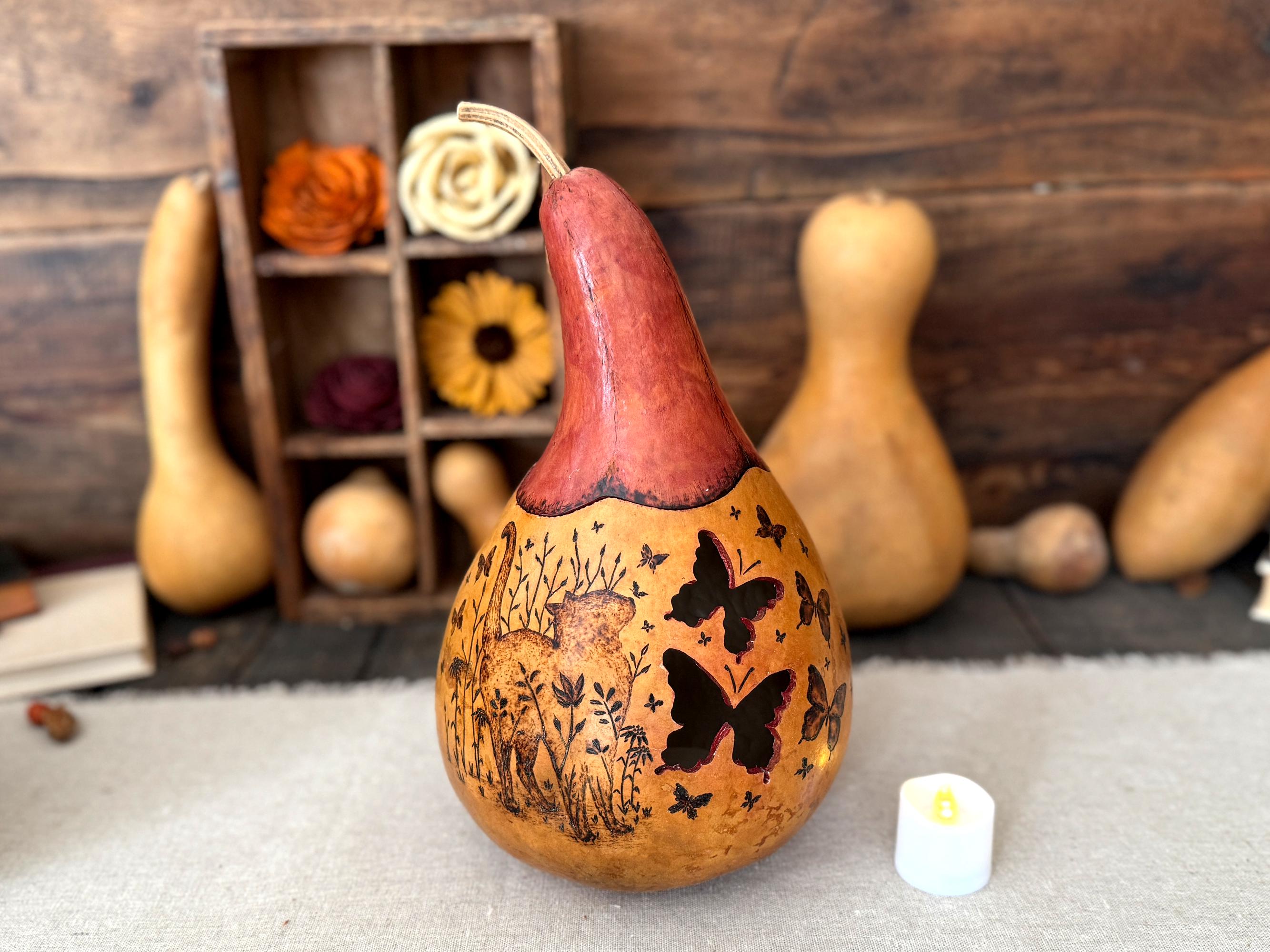 Decorative gourd with butterfly and cat designs on a wooden background