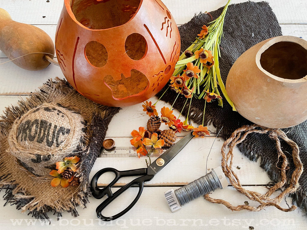 Decorative setting with gourds, scissors, twine, and autumn-themed decor on a wooden surface.