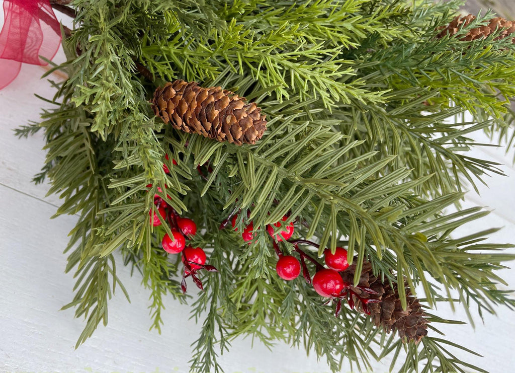 Closeup of  realistic Christmas greenery, red berries, and pinecones on a white background