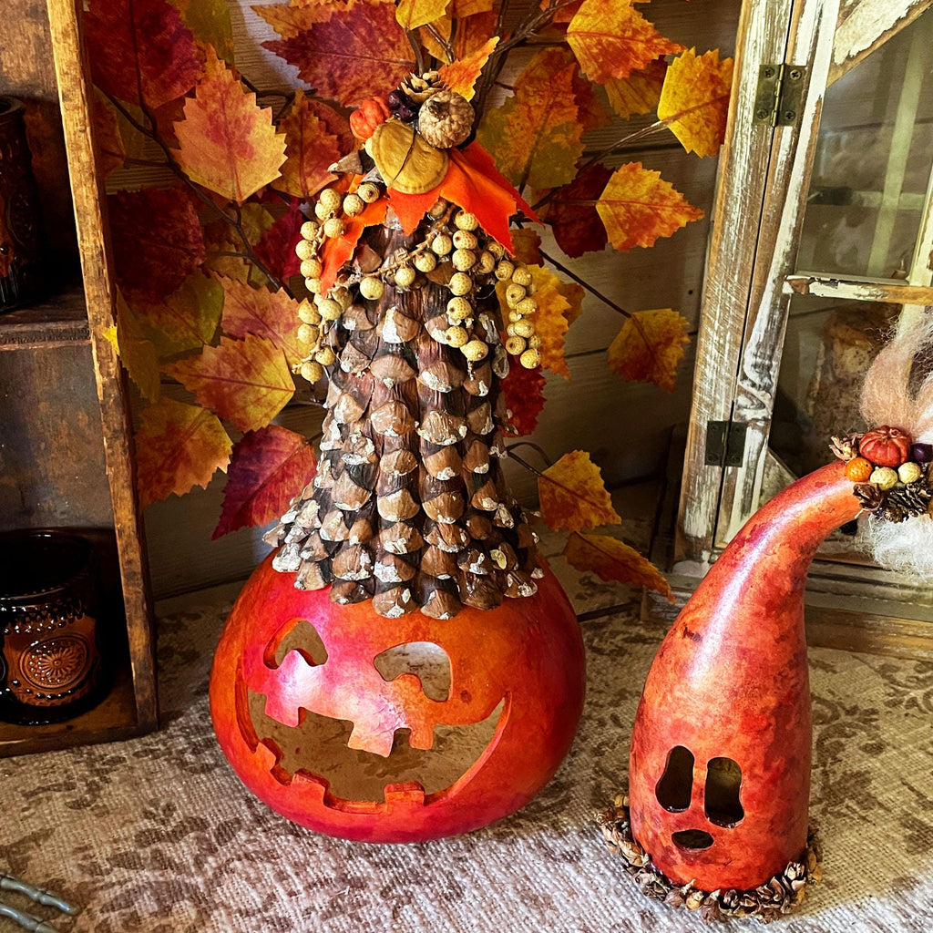 Decorative fall scene with pinecones, leaves, and carved gourds on a rustic surface.