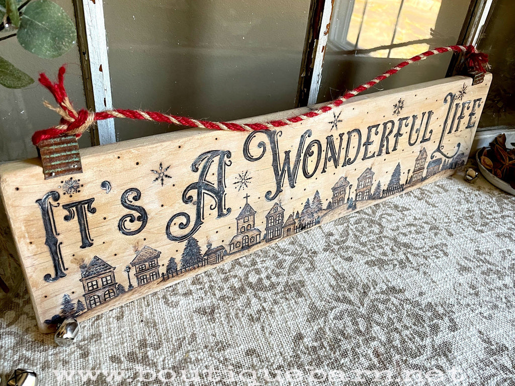 Decorative wooden sign with 'It's a Wonderful Life' text and Christmas-themed design.