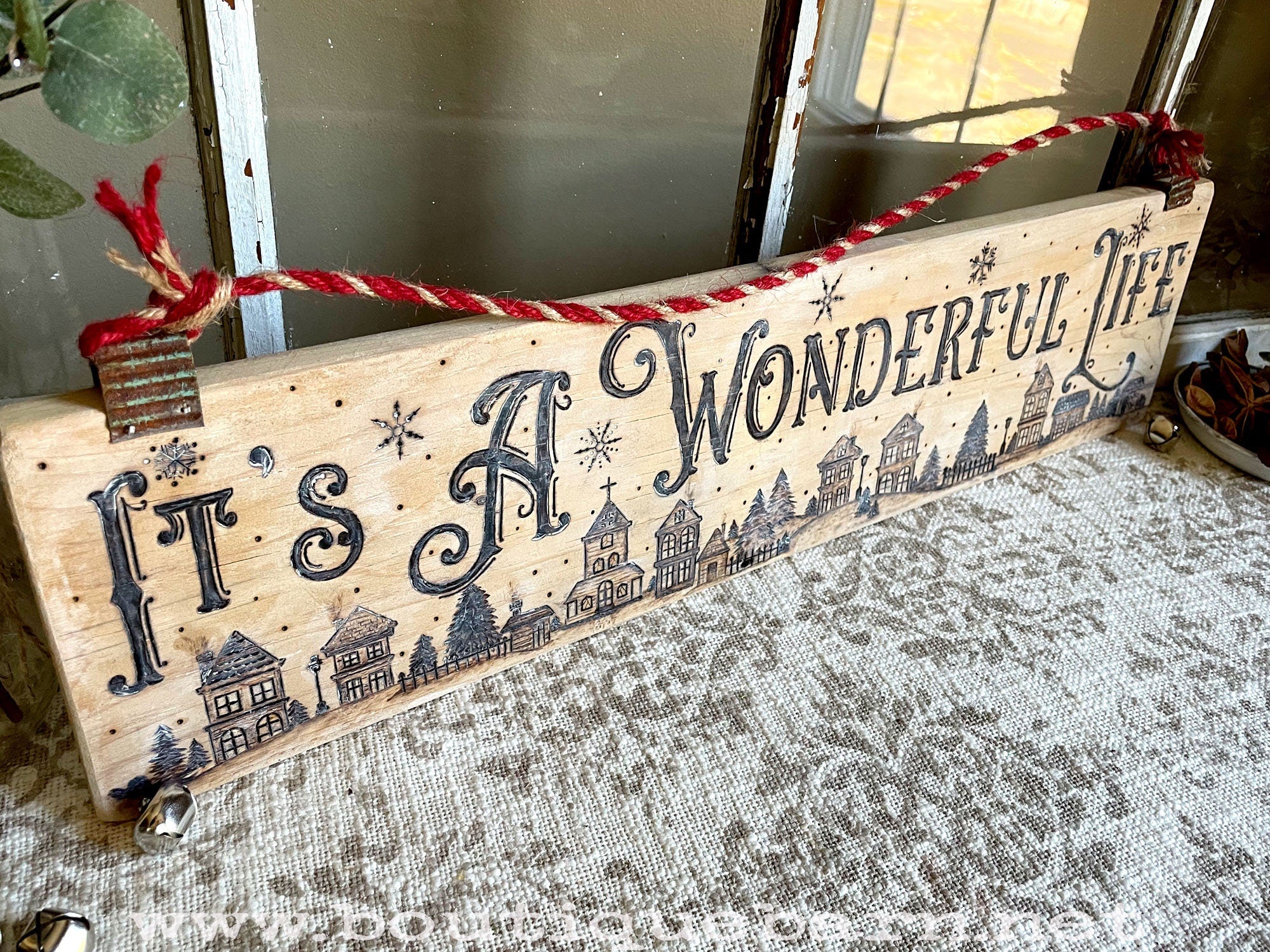 Decorative wooden sign with 'It's a Wonderful Life' text and Christmas-themed design.