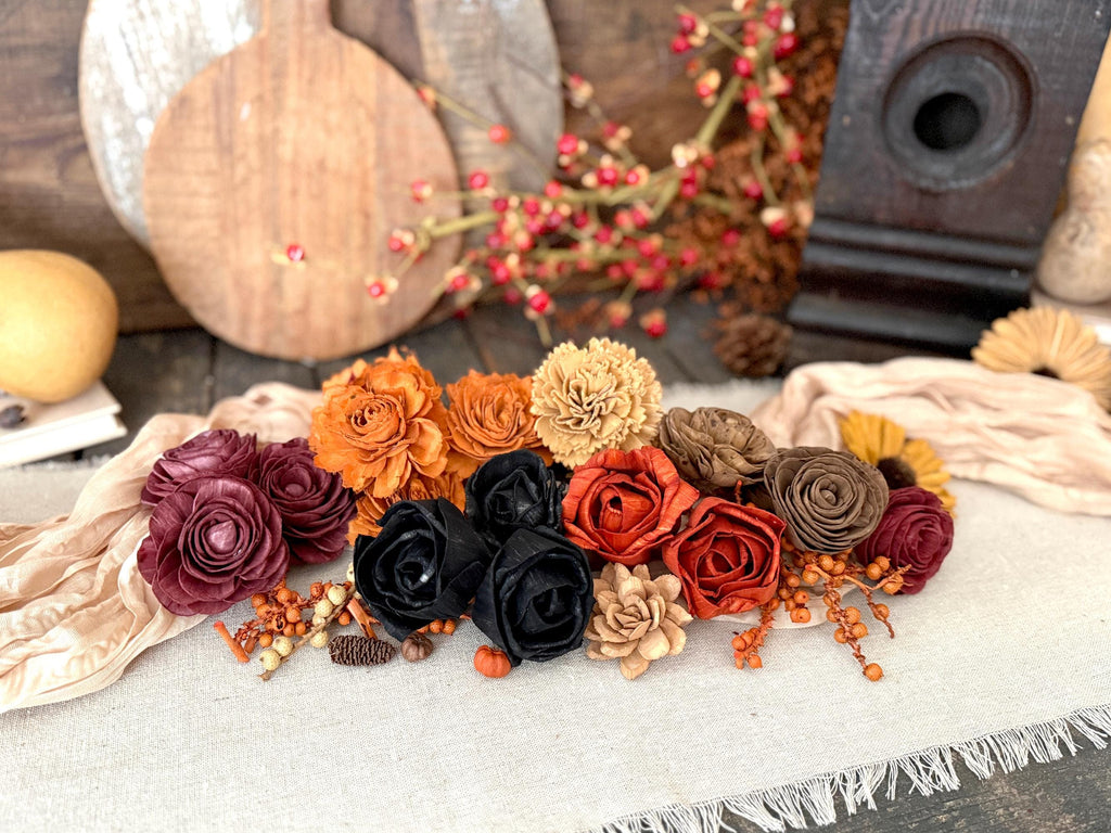 Decorative arrangement of autumn-themed flowers on a textured surface with pumpkins and berries in the background.