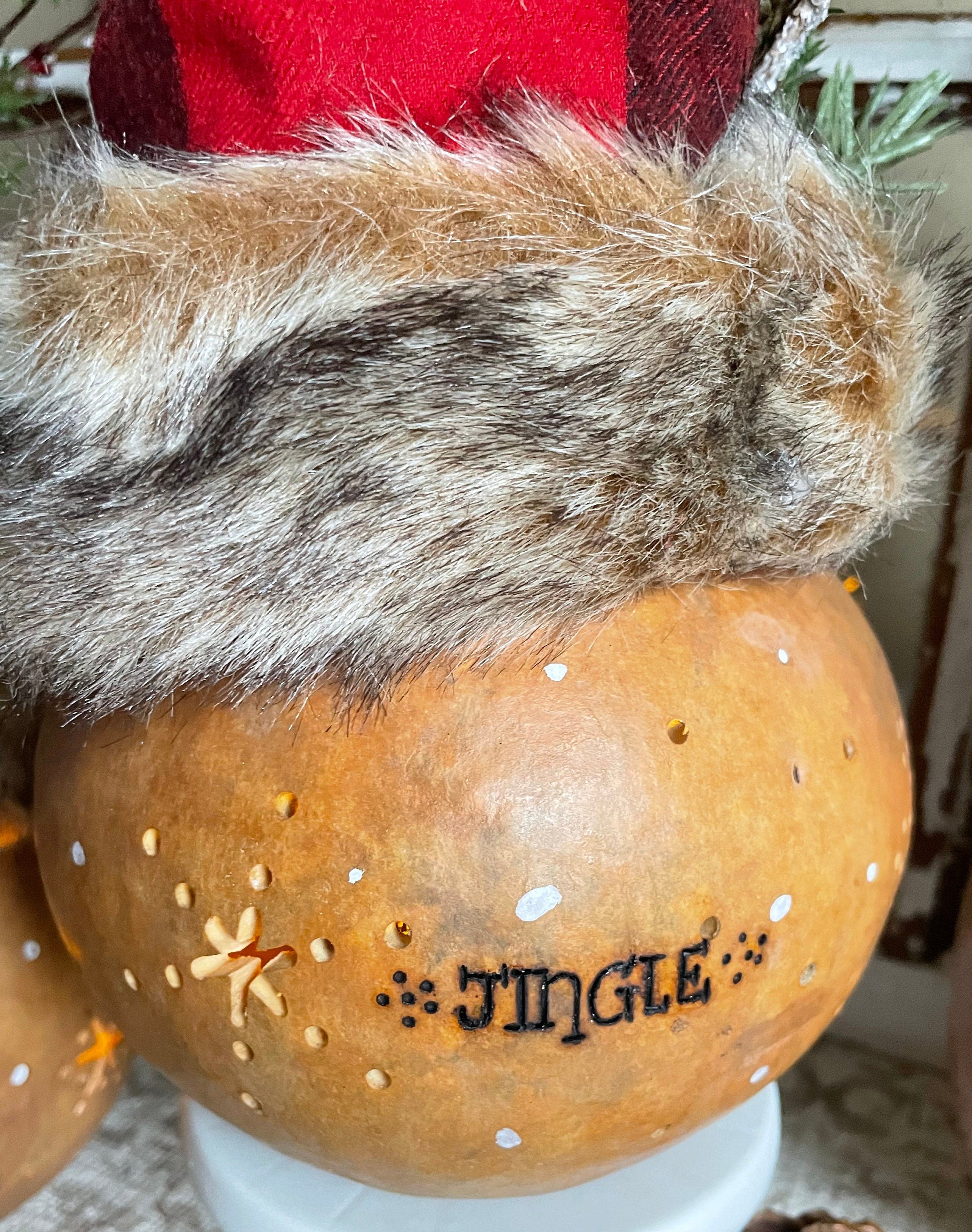 Decorative pumpkin with fur trim and 'JINGLE' text, featuring a red hat.