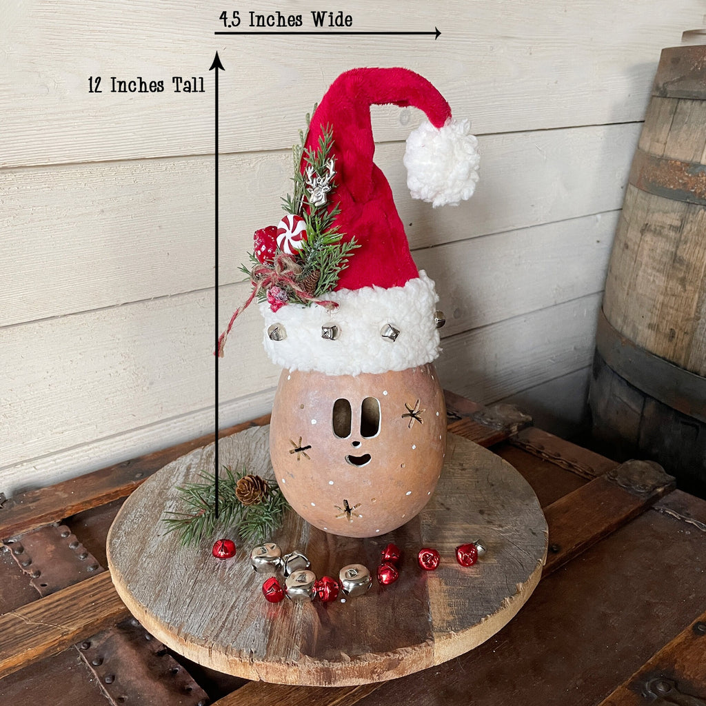 Decorative gourd with a Santa hat on a wooden surface, with measurements indicated.